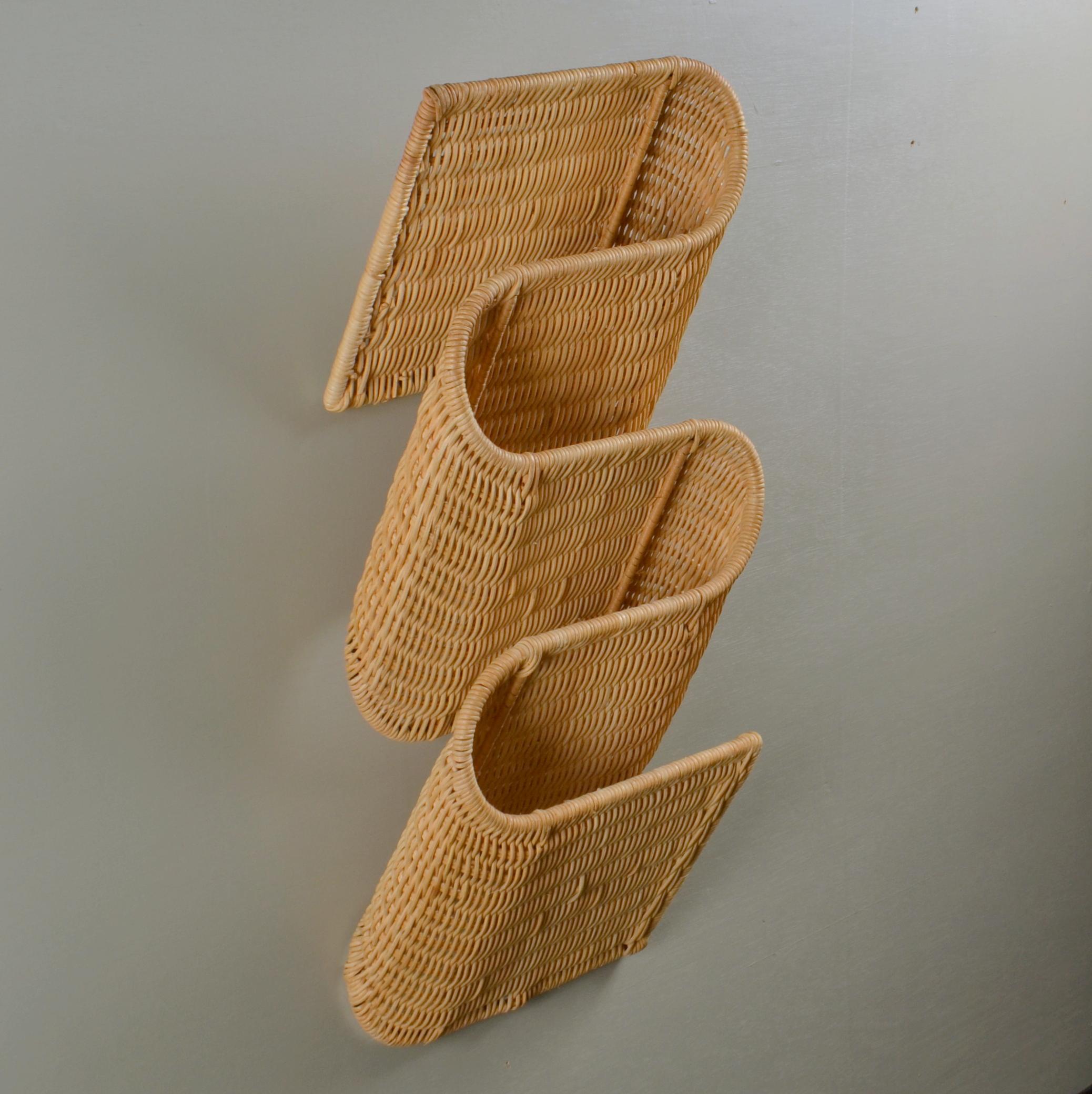 Wall mounted rattan magazine holder is very efficient and decorative storage system that snakes along the wall. It has 4 sections for magazines when hung vertically. The cane work is woven around a metal structure. They are made in Italy,