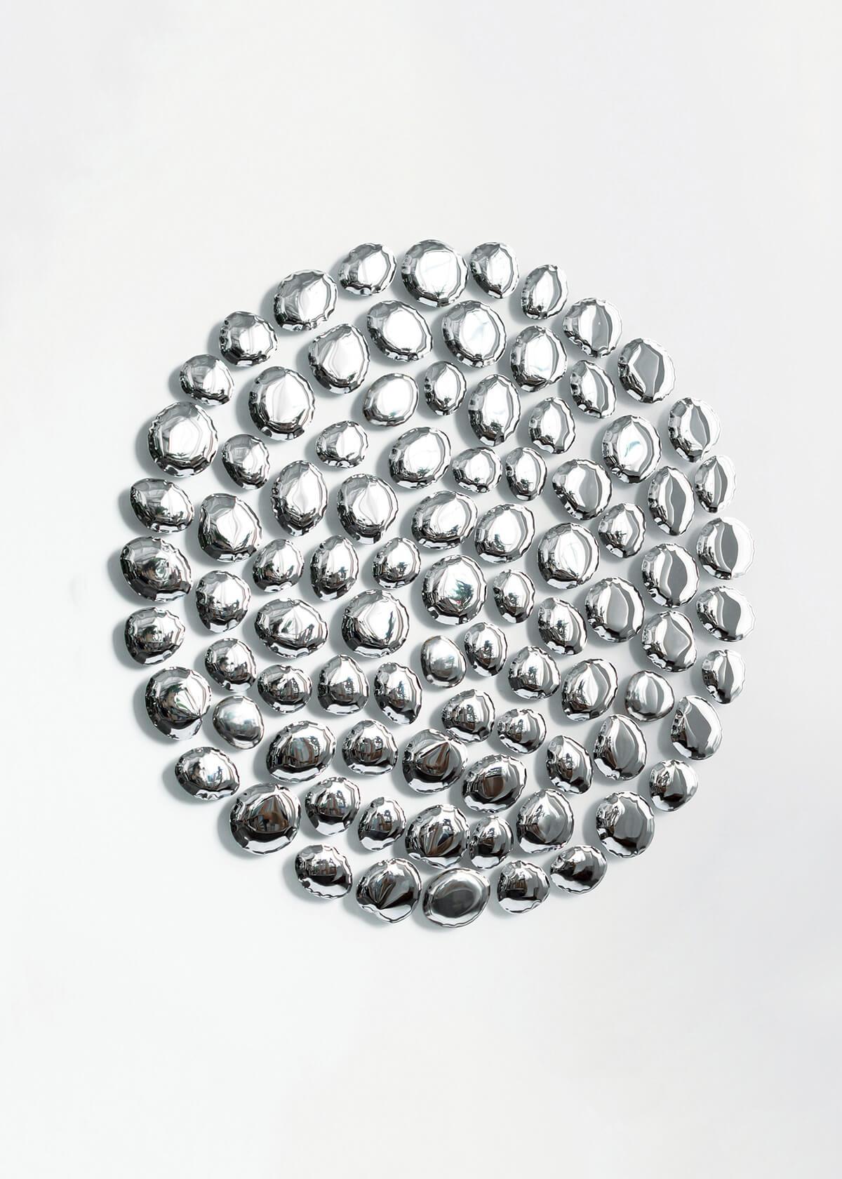 Wandskulptur 'Merkur' von Zieta
Rostfreier Stahl

Durchmesser 150 cm x Tiefe 7 cm

MERCURY ist eine reflektierende Installation aus 89 luftgefüllten, wulstigen, steinartigen Strukturen, die einen ungeordneten Kreis bilden. Die Konstellation der