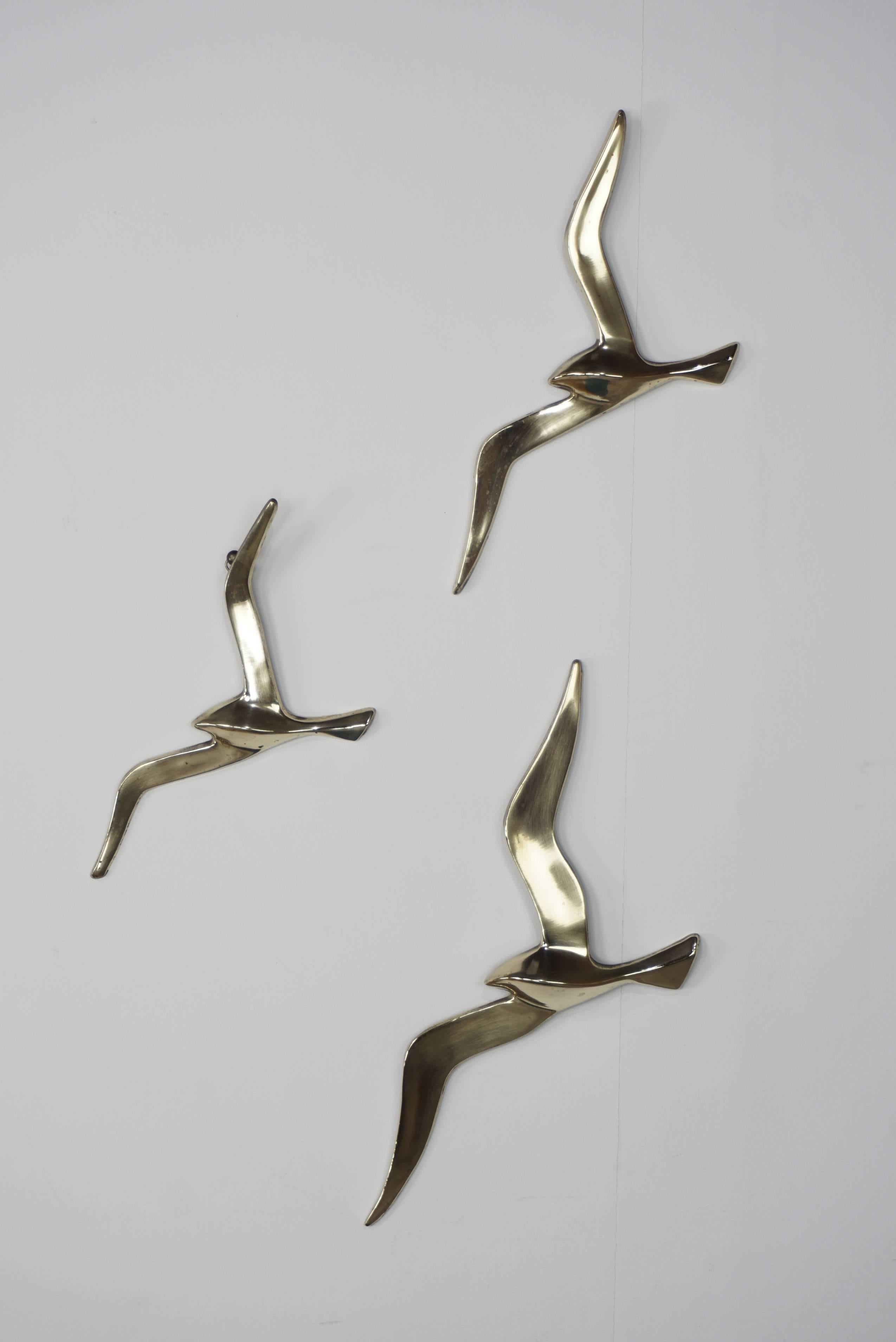 Satz Vögel im Flug, 1960er Jahre Design, Messing, zusammen oder einzeln, Sie können sie mit den Ringen auf der Rückseite hängen.

Maße: H. 36cm x L. 15cm x I. 2cm / H. 28cm x L. 13cm x I. 2cm / H. 25cm x L. 12cm x I. 2cm.
  