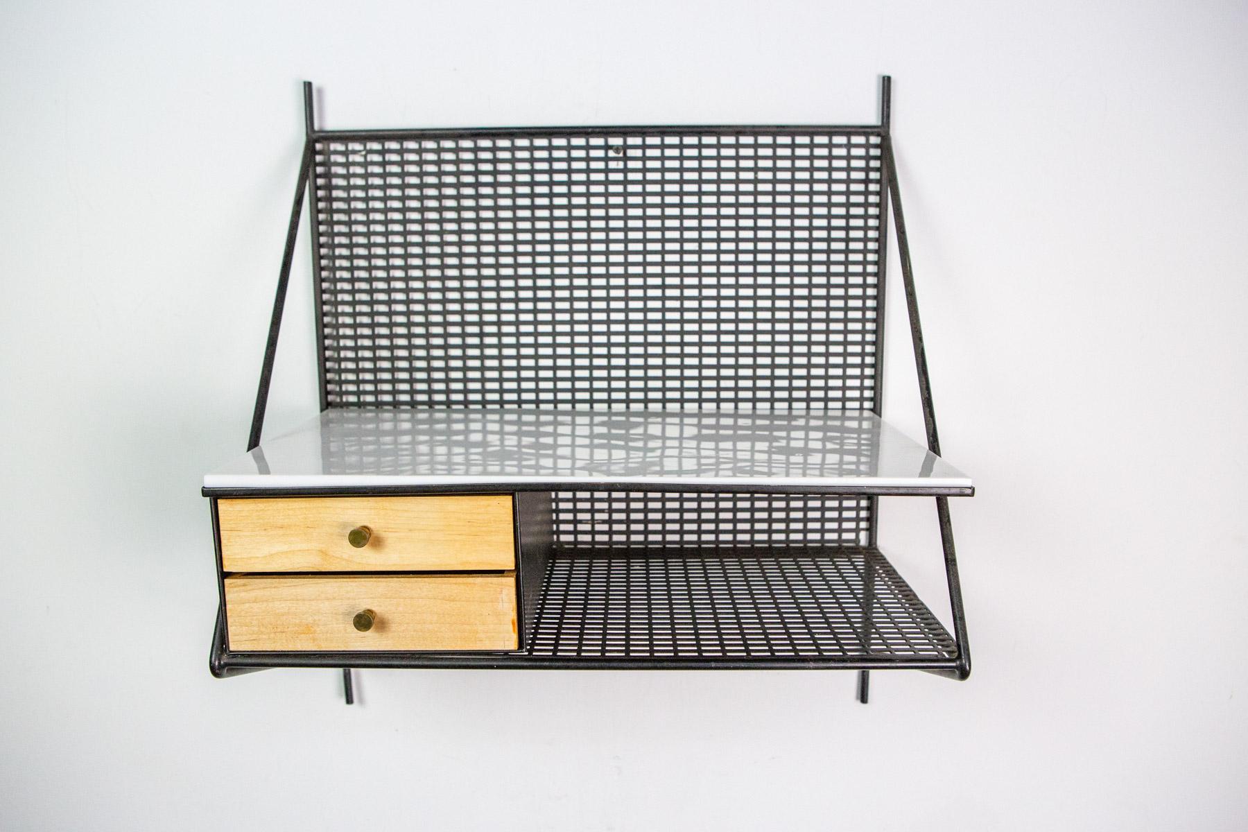 Perfect for almost any space, this wall-mounted shelf by Paul McCobb has two metal shelves, one with a vitrolite glass top, and two small drawers. The combination of iron rod and metal mesh give it a great linear, graphic quality.