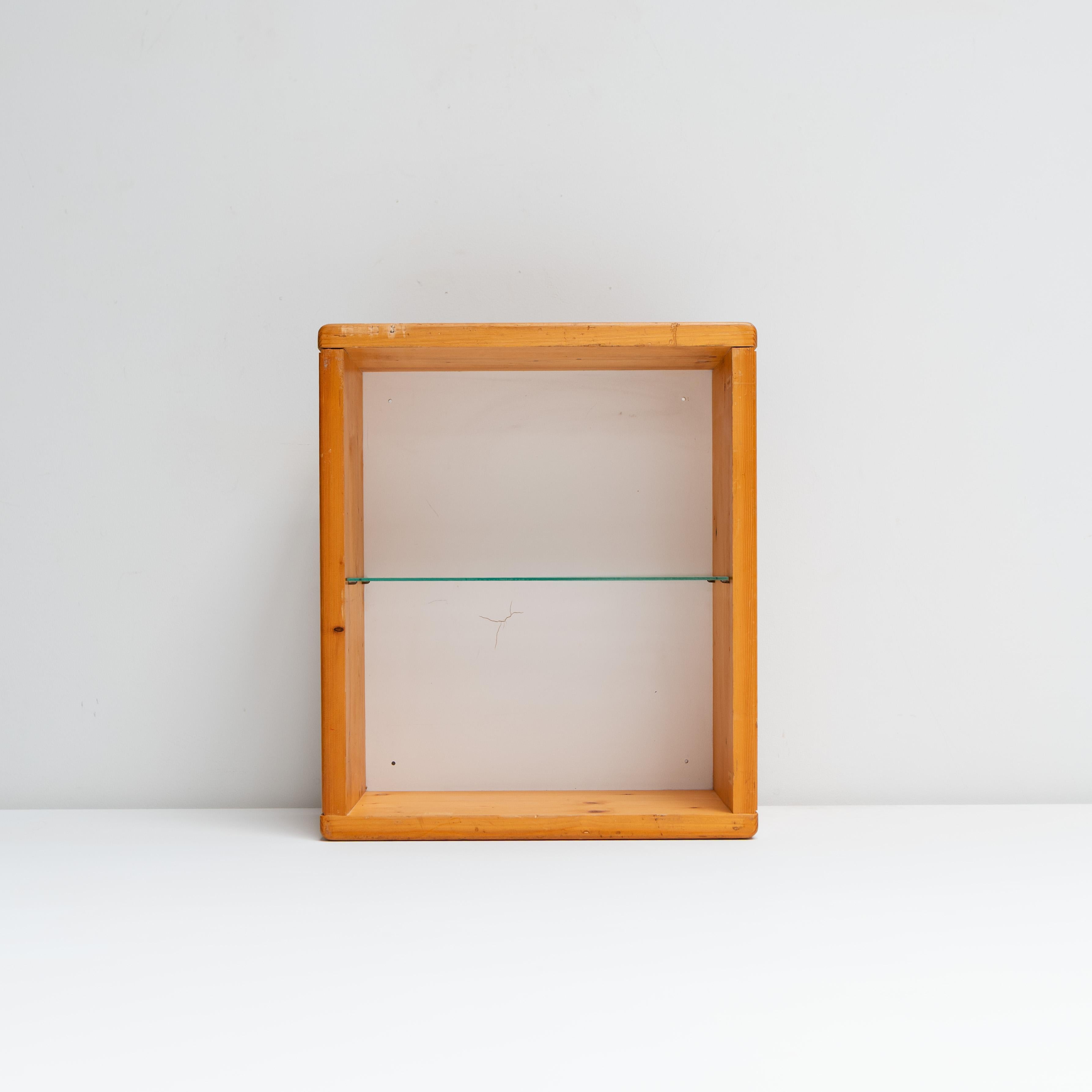 Minimalistisches Wandregal, entworfen von Charlotte Perriand für das Les Arcs. Gefertigt aus massivem Kiefernholz mit einem einzelnen Glaseinsatz, entworfen mit der für Perriand charakteristischen Ausgewogenheit von Nutzen und Wärme. Seine schlichte