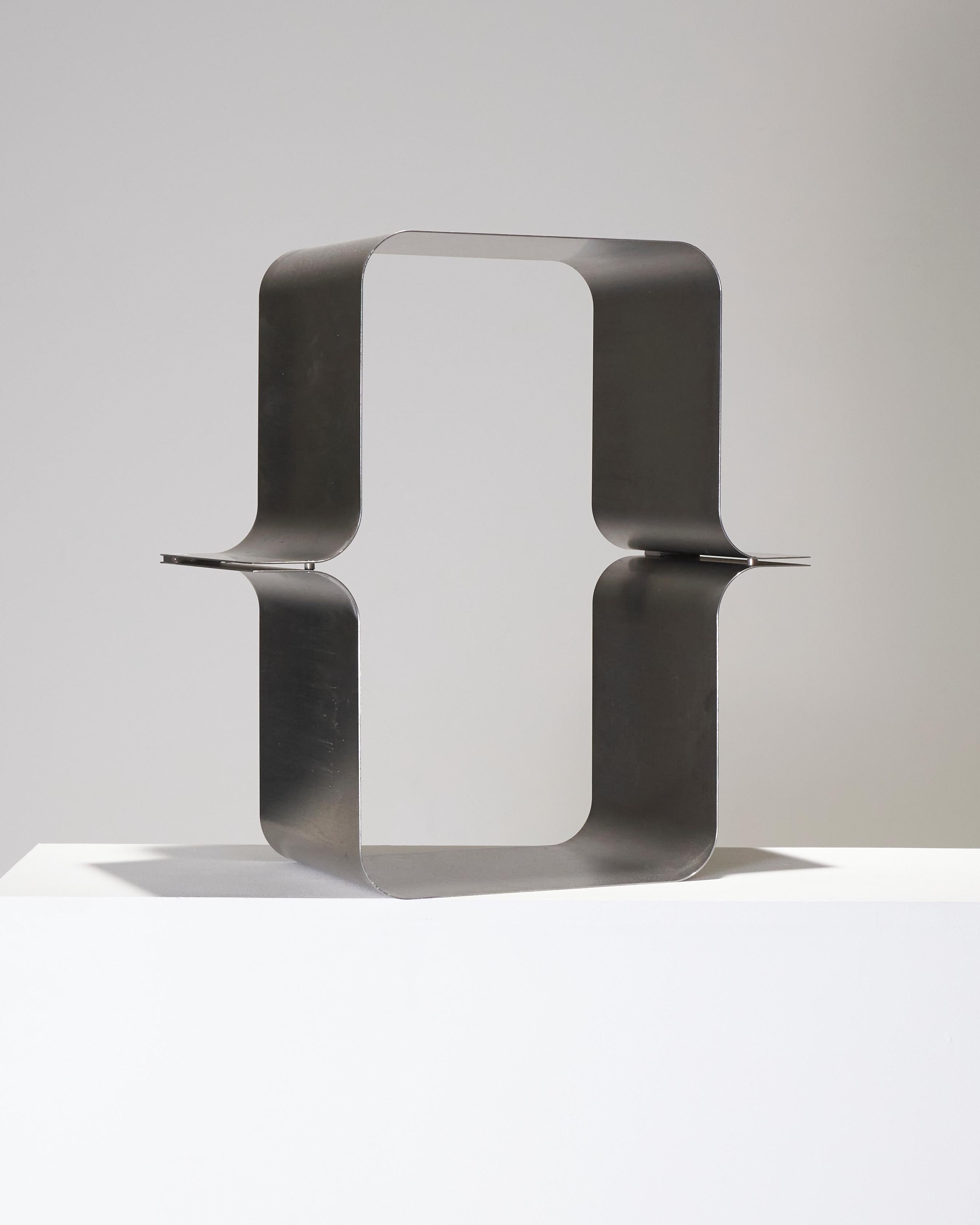 Elegant wall-mounted shelf in brushed steel, signed by Xavier Feal. Designed in the 1970s, it embodies the designer’s distinctive minimalist and sculptural aesthetic.  This rectangular shelf stands out with its two curved metal sections meeting in a