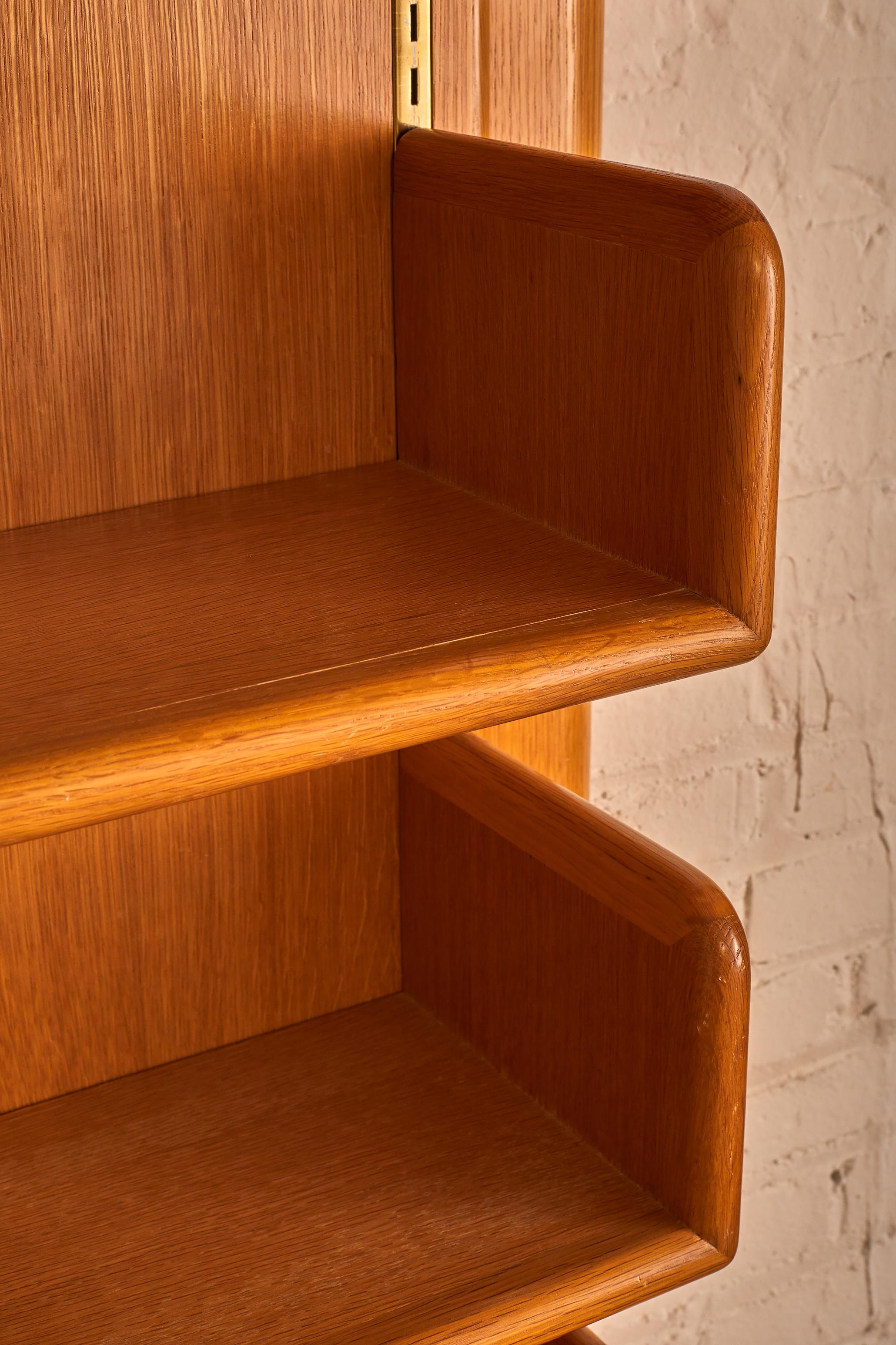 Wall mounted shelving Unit by Warren Platner featuring 6 shelves with brass enclosures.