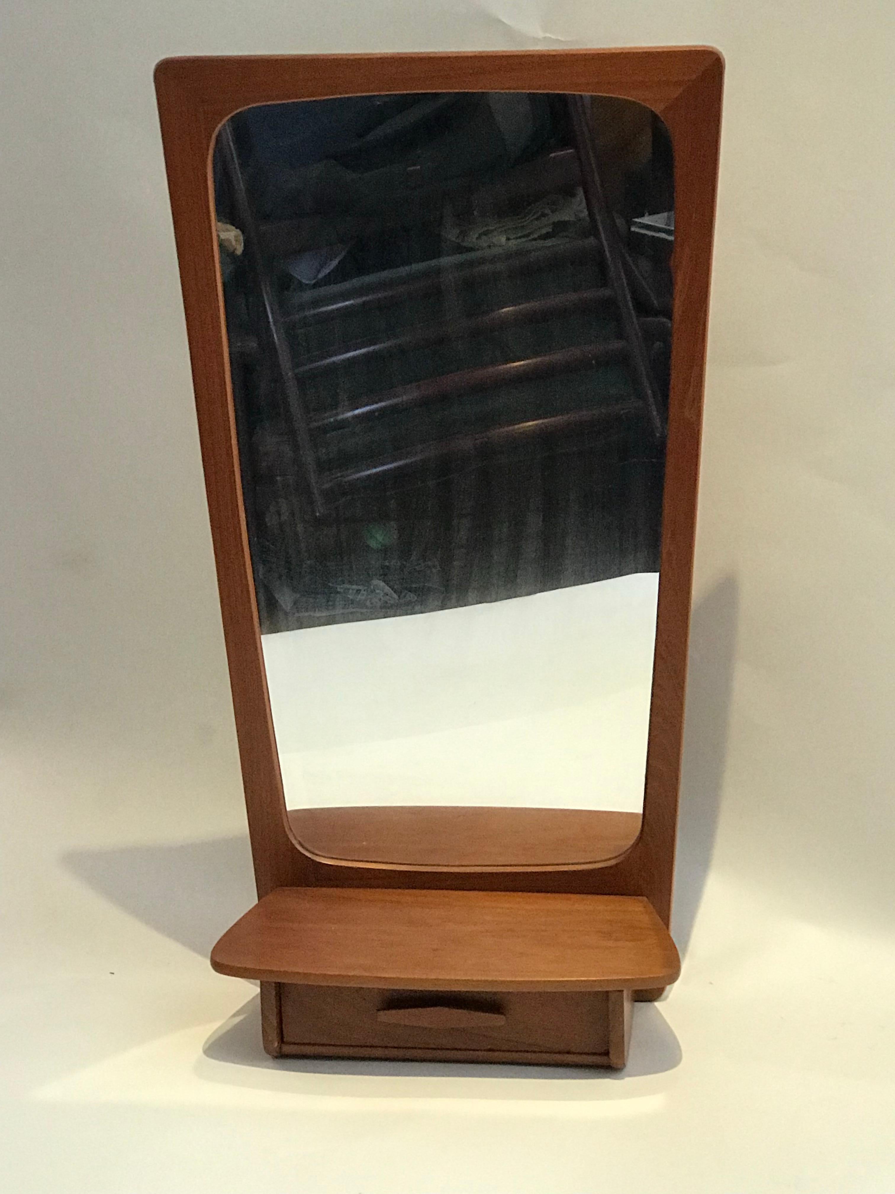 Wall-mounted teak mirror with storage or vanity.
Handsome teak wall mirror with attached storage drawer and shelf. Great for entry way or bedroom. Stylized frame and drawer pull complete this Mid-Century Modern design.