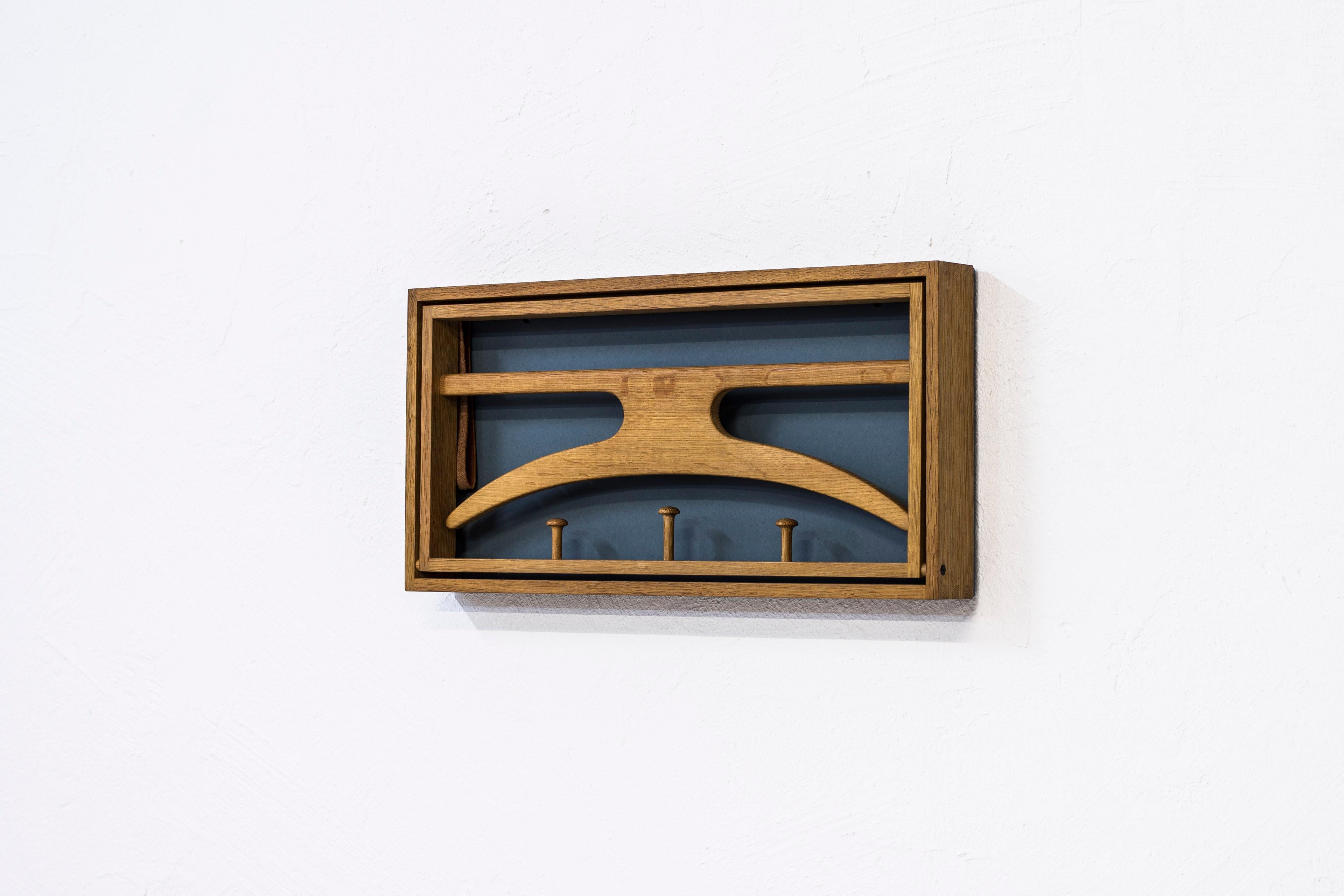 Wall-mounted valet designed by Adam Hoff & Poul Østergaard. Produced in Denmark during the late 1950s by Virum Møbelsnedkeri. Solid oak frame with visible joinery, original leather straps and lacquered masonite. Excellent condition with very light