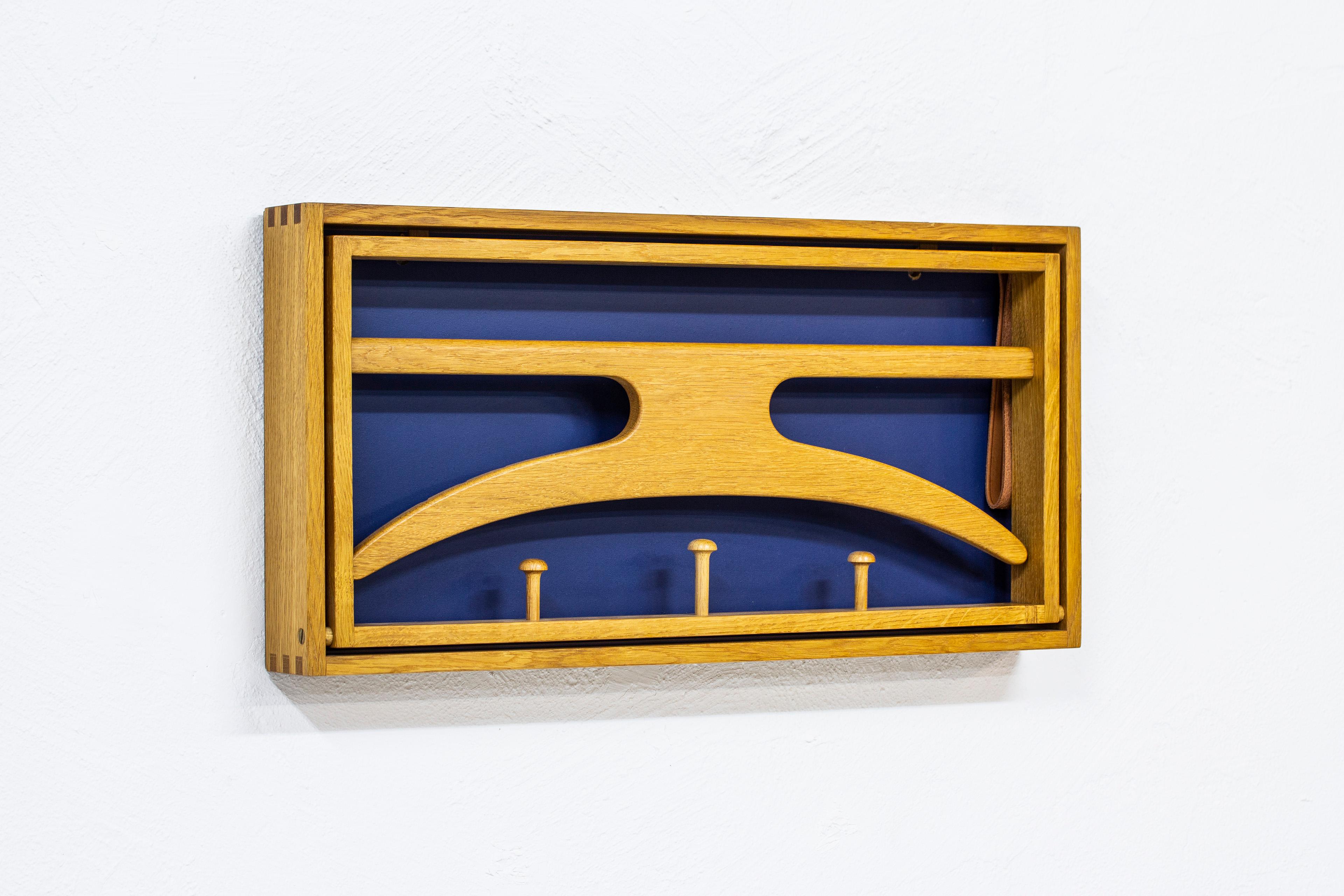 Wall-mounted valet designed by Adam Hoff & Poul Østergaard. Produced in Denmark during the late 1950s by Virum Møbelsnedkeri. Solid oak frame with visible joinery, leather straps and blue lacquered back part. Very good condition with light wear and