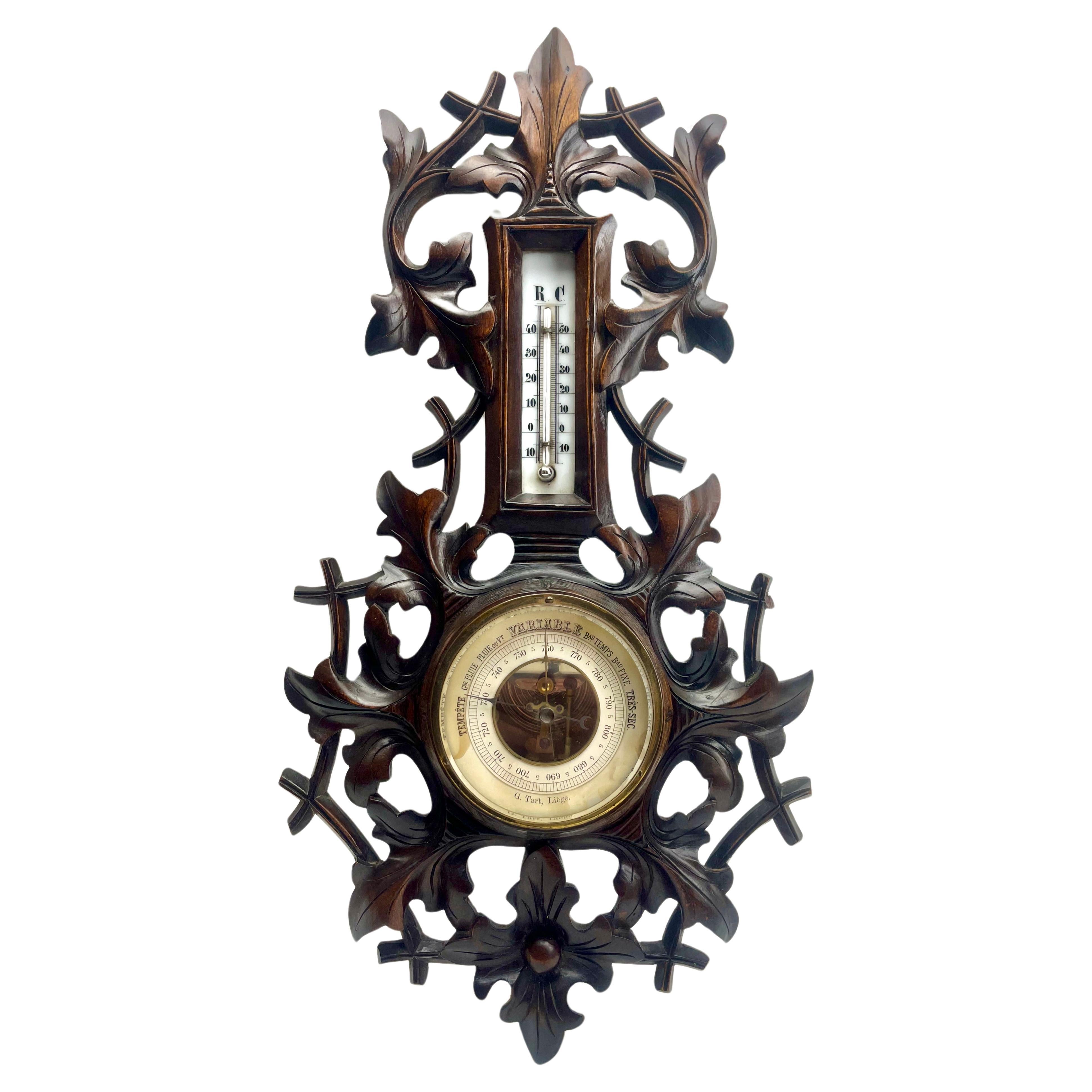Wall-mounted weather station in carved walnut made in Liege Belgium by G.Tart. 
High quality mechanism with jeweled movement barometer and thermometer (in centigrade)
Unusual design with high relief C-scrolls and flowers in Rococo style (from theArt