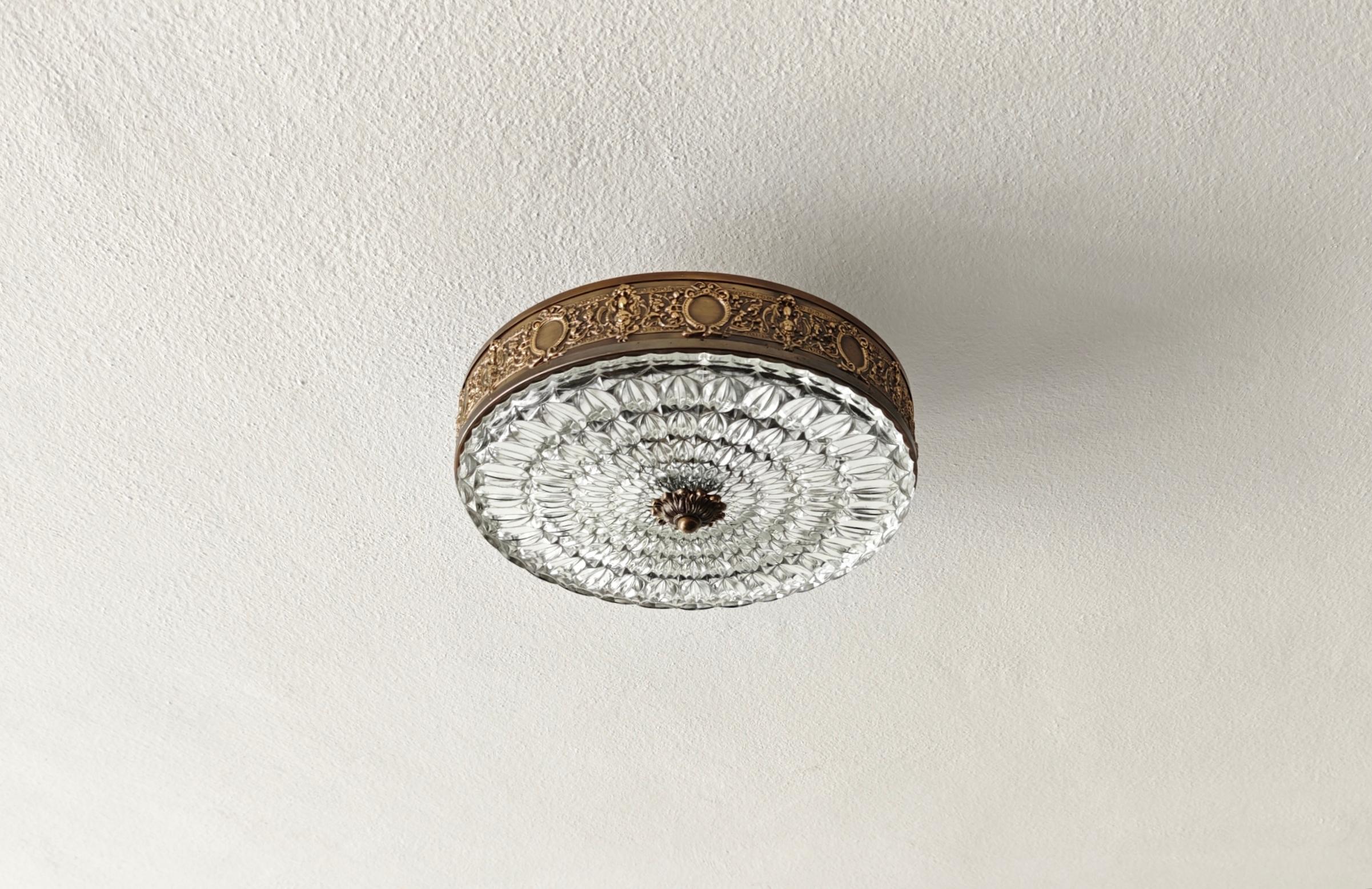 Lámpara de techo o de pared. Marco de bronce/latón trabajado, con 4 luces interiores. Cierra un hermoso cristal transparente con múltiples facetas, de una calidad realmente excelente. También puede colocarse en la pared gracias a tres orificios,