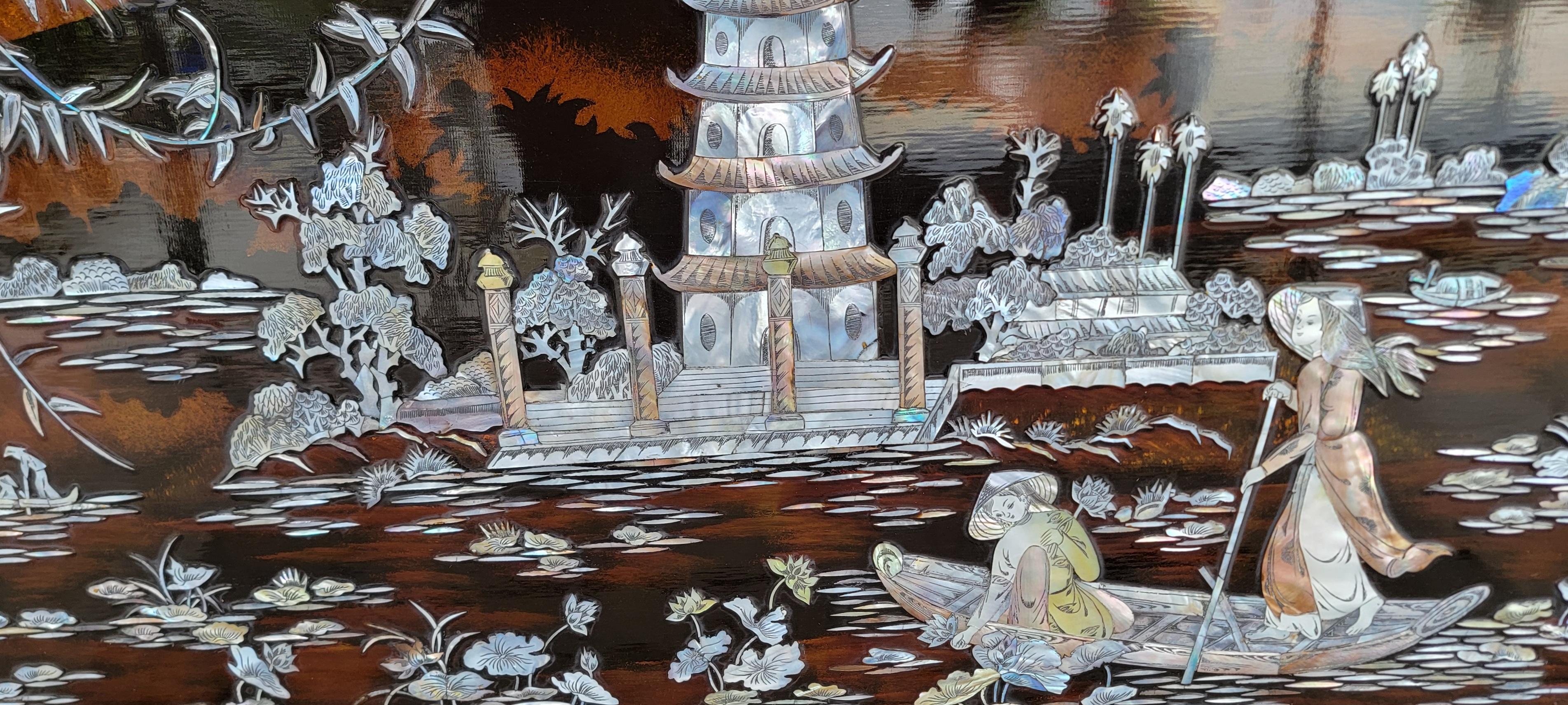 Vietnamesische Wandtafel aus geschnitztem Perlmutt und Lack. Mit einer Pagode in der Mitte, Flora, Wasser und Frauen in einem Boot. Circa. 1970's.

19,5 Zoll hoch.
31,5 Zoll breit.
0,5 Zoll tief.
