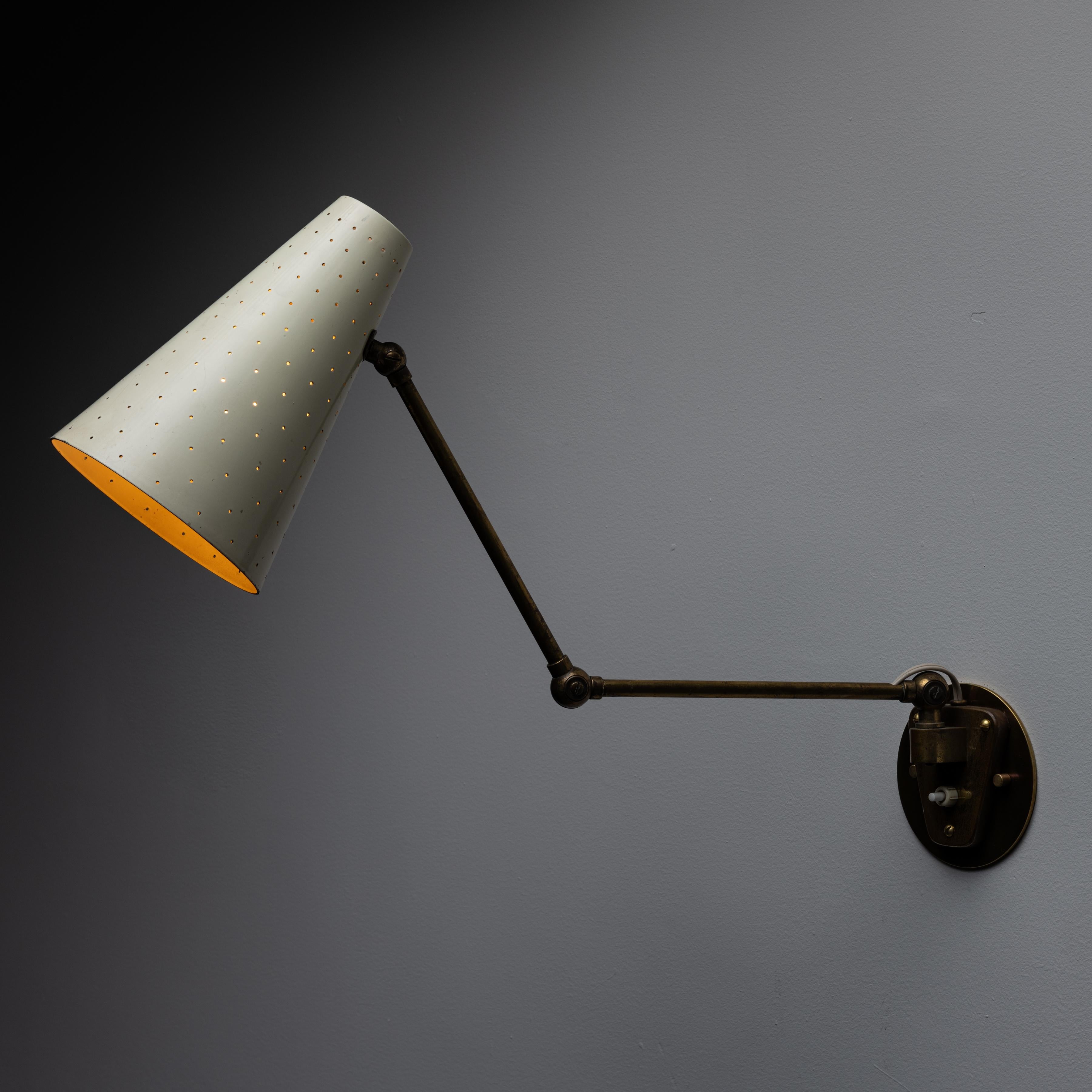 Wandleuchter von Giuseppe Ostuni für Oluce. Entworfen und hergestellt in Italien in den 1950er Jahren. Ein emaillierter, perforierter Schirm mit einer dreieckigen Armatur. Die Mehrfachkupplungen ermöglichen eine fließende Positionierung. Diese Lampe