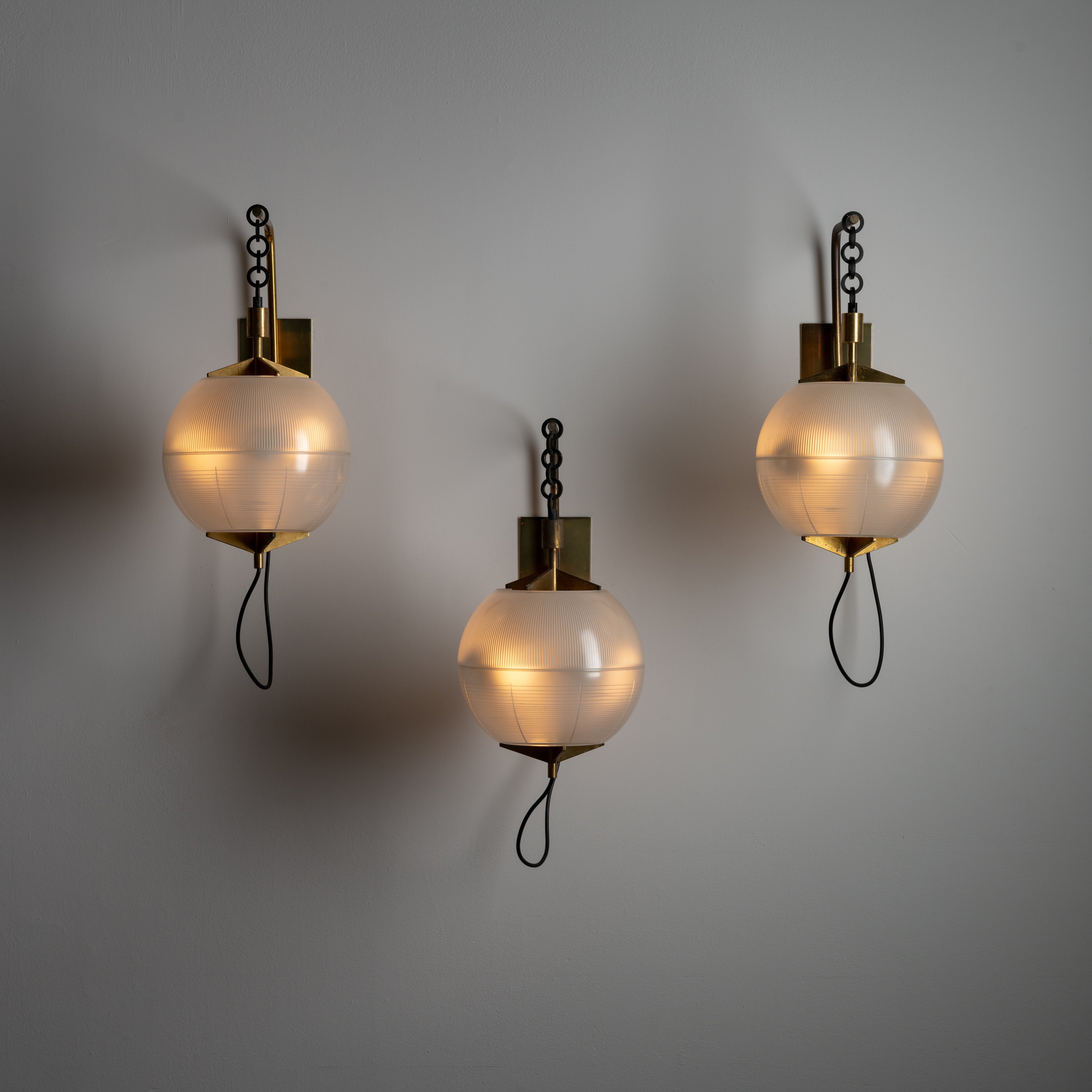 Wall Sconces by Greco. Designed and manufactured in Italy, circa 1950. Architectural sconces by greco, with suspended reeded glass sphere shades. The sconces feature steel chain links as the method of suspension, providing a nice contrast between