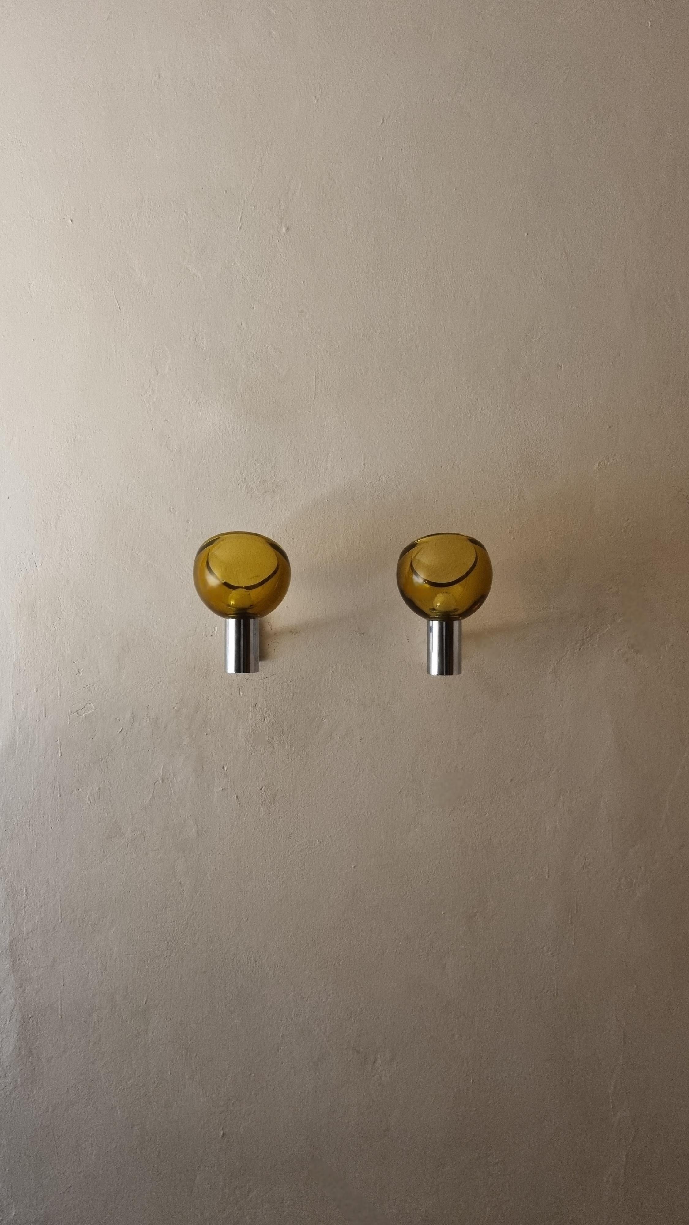 Juego de 2 apliques de pared diseñados por Flavio Poli para Seguso en los años 60, estructura de latón cromado, cristal grueso naranja ahumado.
Excelentes condiciones, funcionando perfectamente.

Nació en Venecia en 1900,  Poli fue el primero en