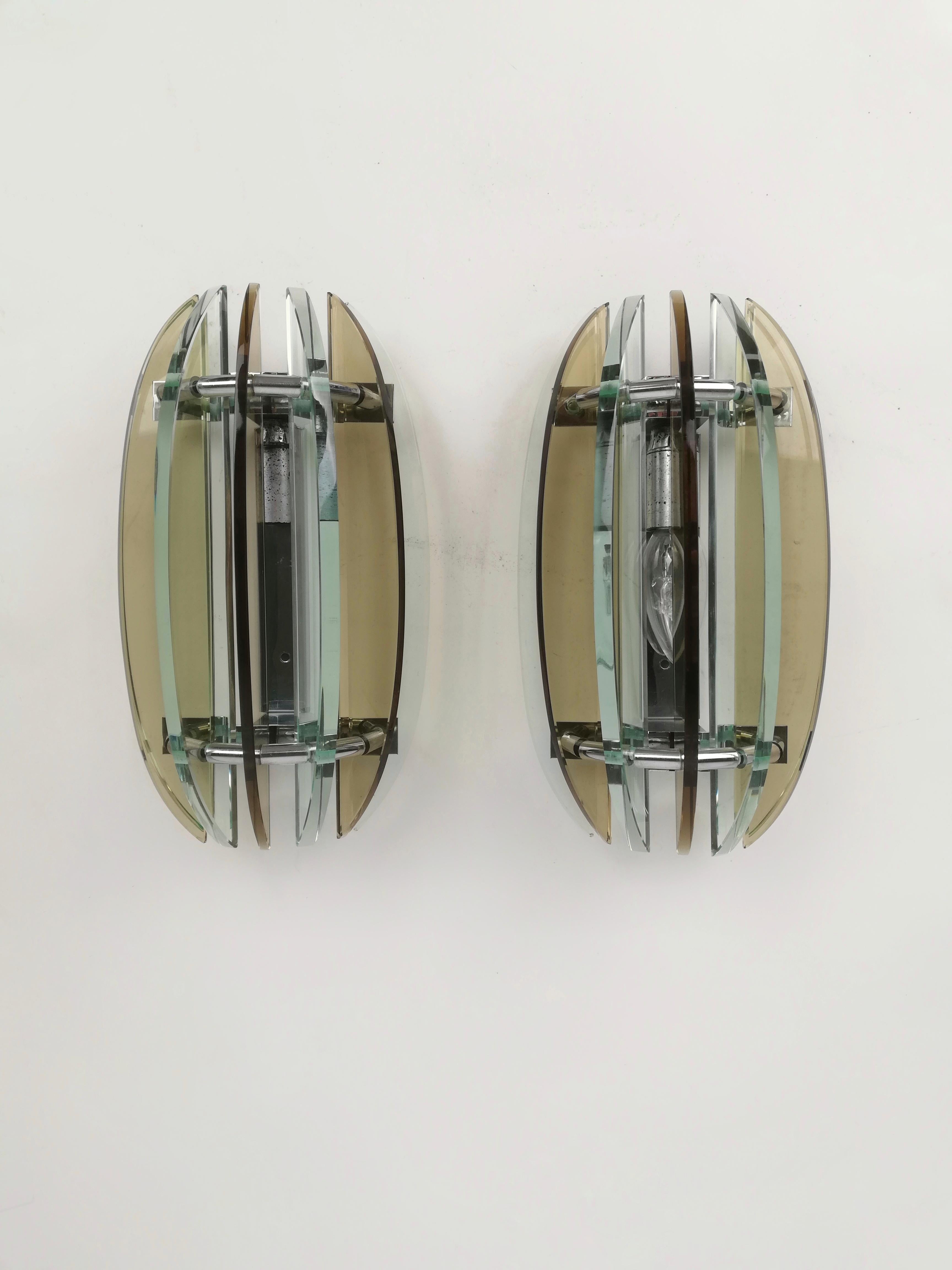 A pair of wall sconces dating from the 60s and 70s and produced by the VECA company, a famous Italian company known for glass production such as Fontana Arte durnig the 20th century.
Glass segments are fixed to a chromed metal structure of 2