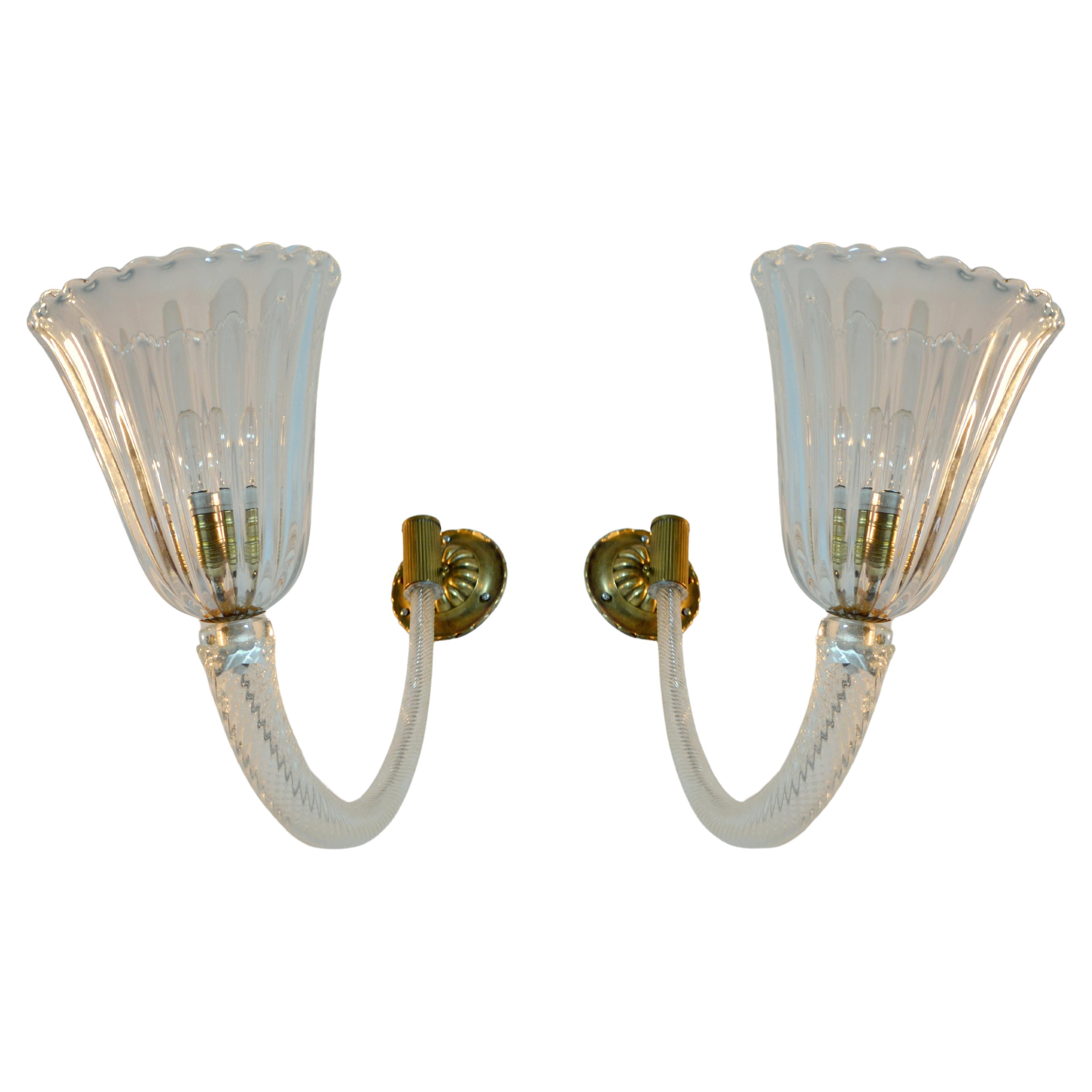 Pair of Mid-Century Murano wall sconces clear blown glass and brass 1940-50's, attributed to Barovier & Toso. The shades are connected to the wall by twisted glass bowed arms and can be applied as up - or downward lamps. The scallop shades like