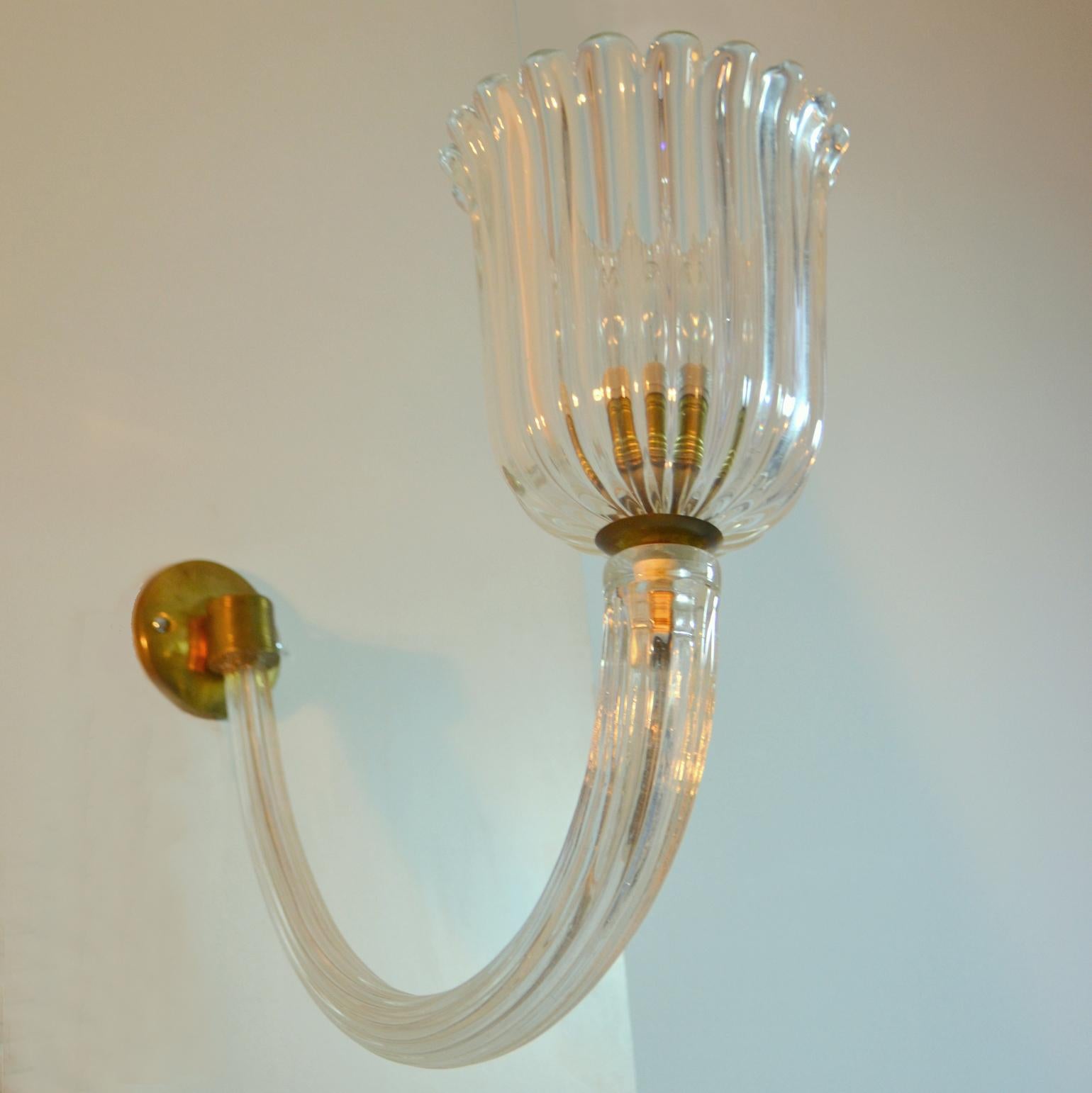 Pair of elegant mid century curved arm Murano glass and brass wall sconces attributed to Barovier & Toso 1940's. The scallop shades lead by the bowed ribbed arm to the brass wall mount.