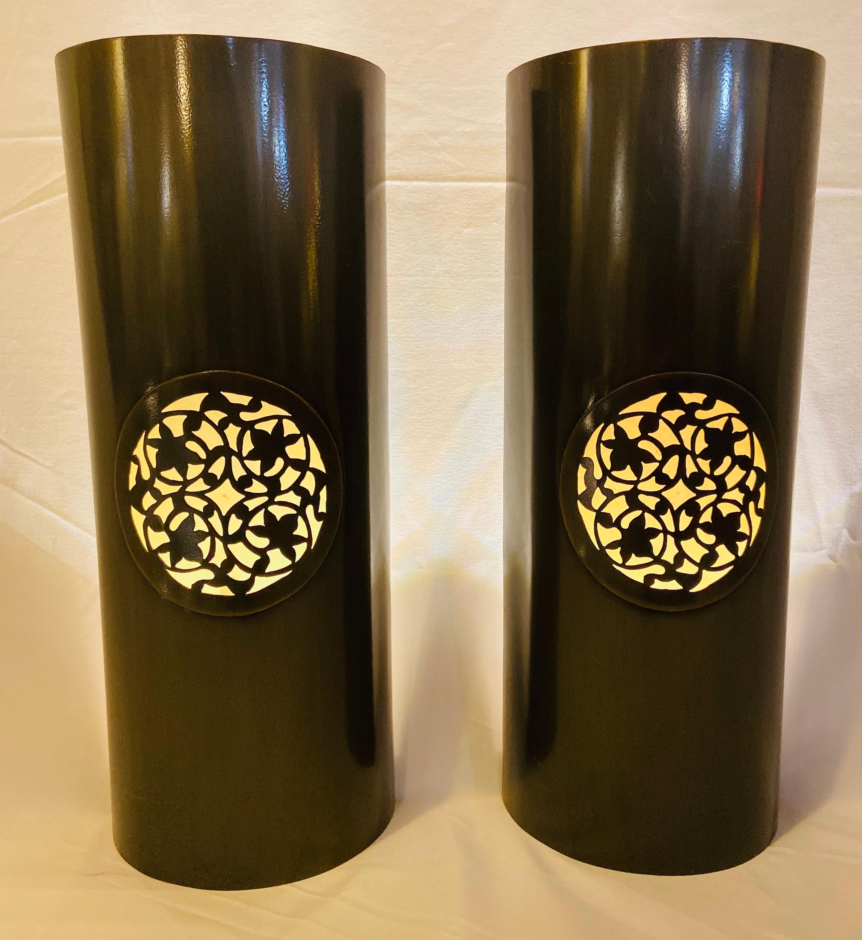 A vintage pair of handmade Moroccan wall sconces or lanterns in Pewter finish. The sconces feature a  semi-cylindrical shape and are embellished with a beautiful round leaves carved design emitting a soft and warm light for a cozy and exotic