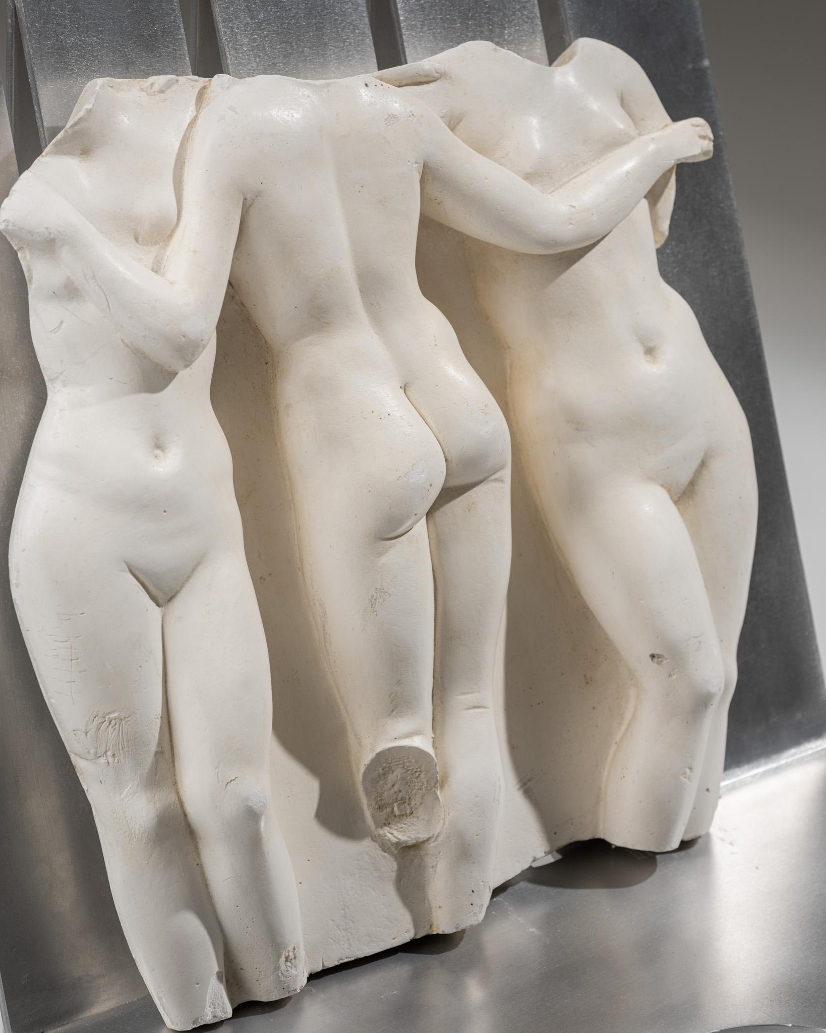 Bas-relief depicting the Three Graces, mythological figures from Greco-Roman tradition. Made of white-tinted resin, it is inspired by the model kept at the Louvre Museum. This cast comes from the National Museum Casting Workshops and was made from
