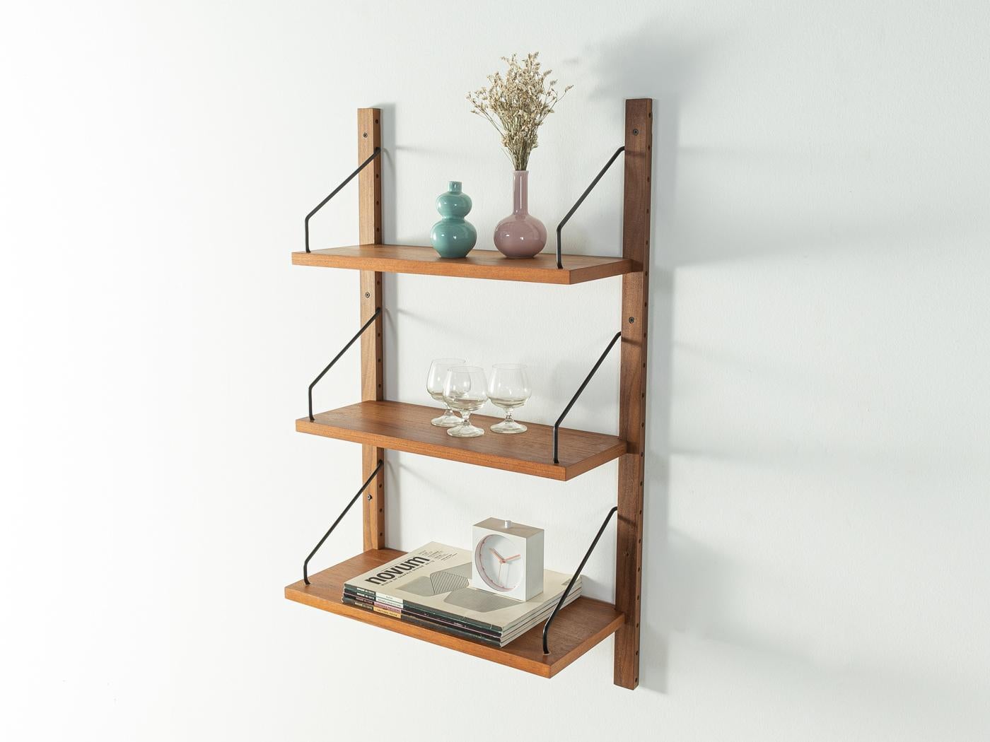 Classic shelving system from the 1950s. The high-quality shelves are veneered in teak. The system consists of three shelves and two wooden ladders.
Quality Features:

 accomplished design: perfect proportions and visible attention to detail
