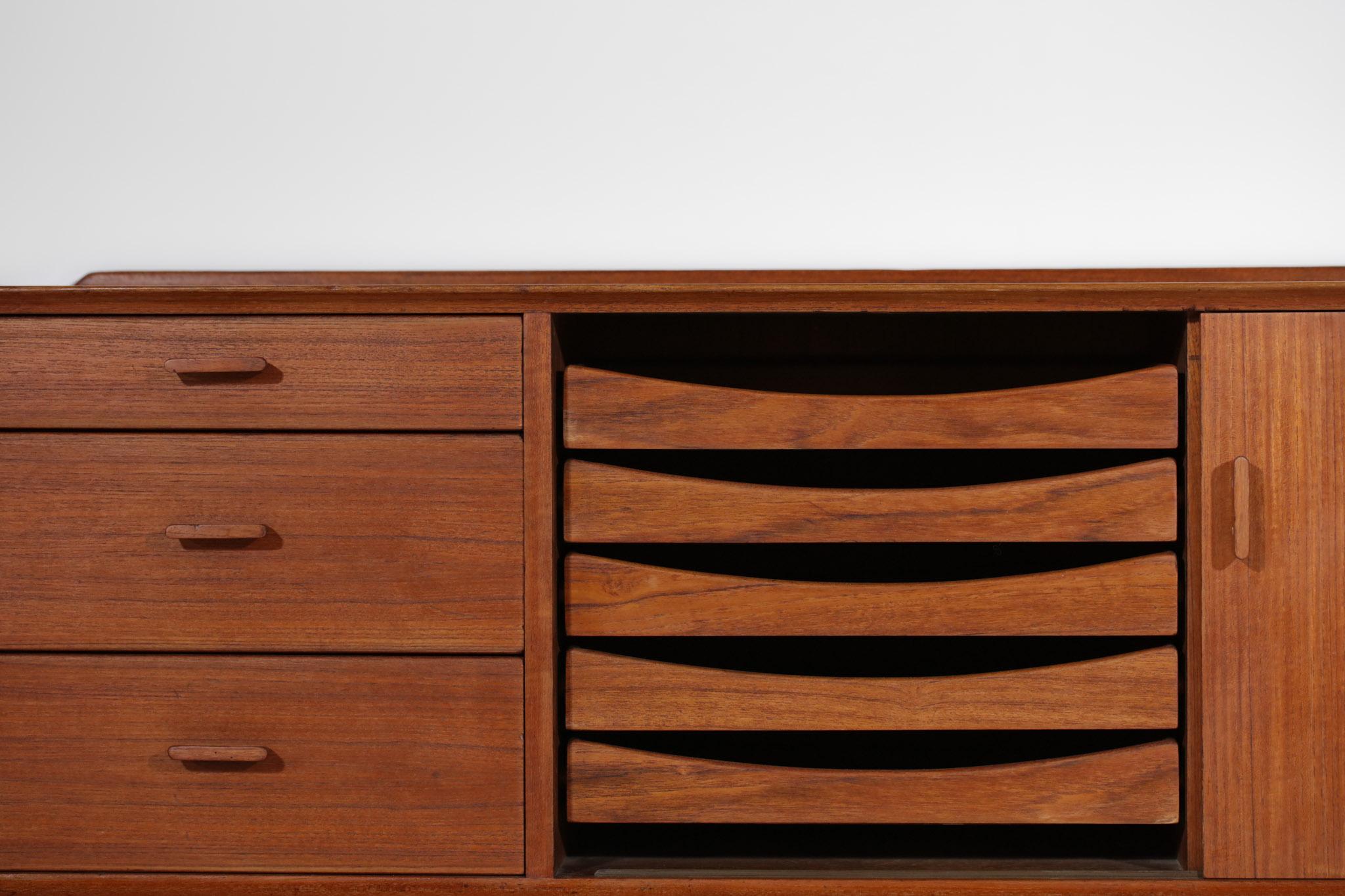 Wall unit from the 60's by designer Arne Vodder published by Sibast. Structure in solid teak and veneer. The front consists of five drawers, a sliding door opening from the adjustable shelves, three drawers of different sizes in solid teak and on