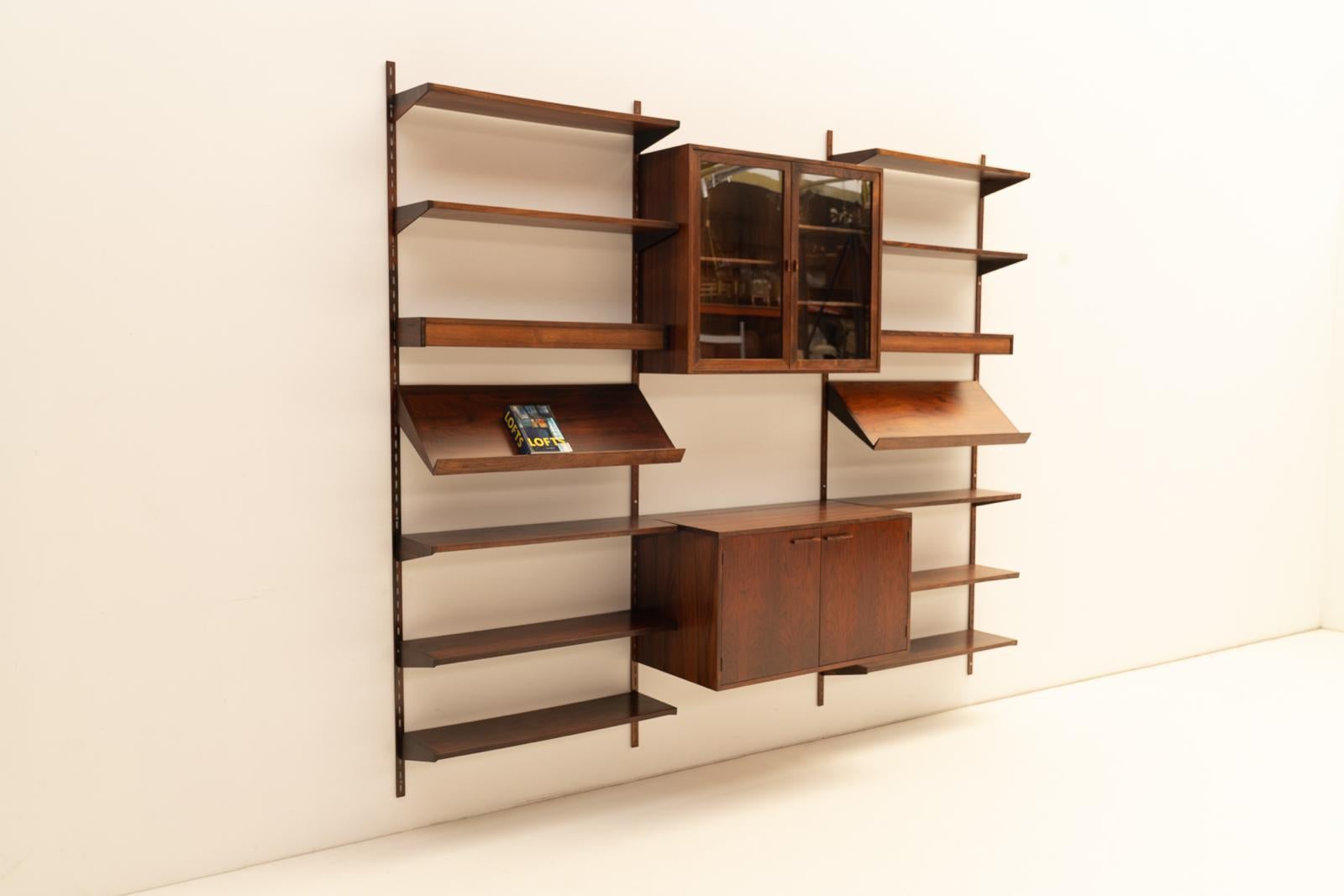 Crafted from luxurious wood, this shelving system exudes the timeless simplicity and functionality that are hallmarks of Scandinavian modernism.

This modular wall unit includes a combination of open shelves and a drop-front cabinet, perfect for