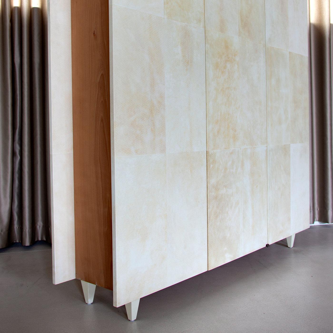 An exclusive design by Renzi e Reale, this wall unit cabinet is entirely wrapped in matte natural parchment and features three doors that open to reveal an interior in natural wood with three shelves in each section. The tall, rectangular structure