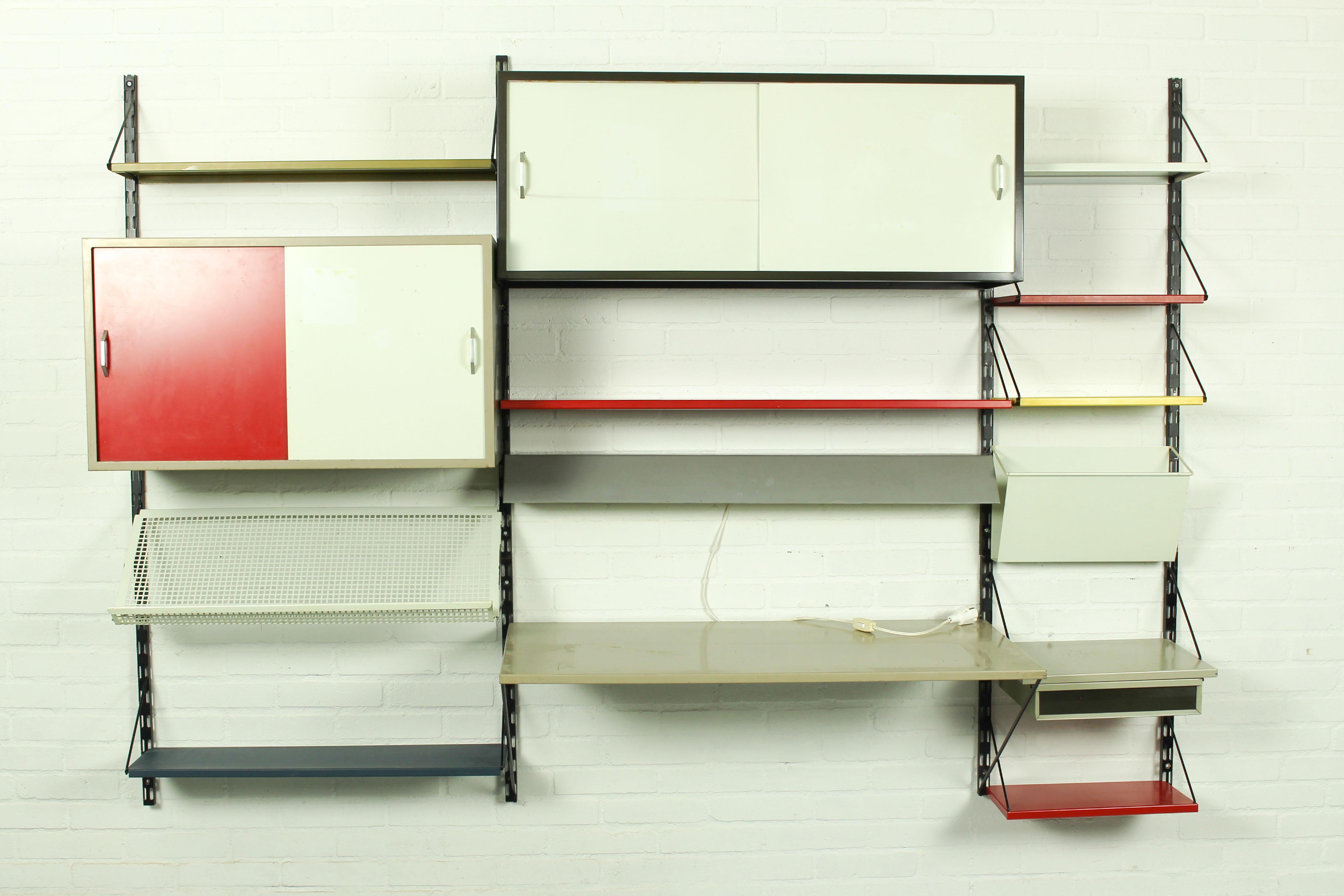 Vintage industrial wall system / bookshelves, designed by Tjerk Reijenga for Pilastro, Holland 1960s. Very nice and complete wall unit with some rare pieces included, it contains 2 cabinet, a die cut magazine shelve, a grey/taupe lamp, a desk