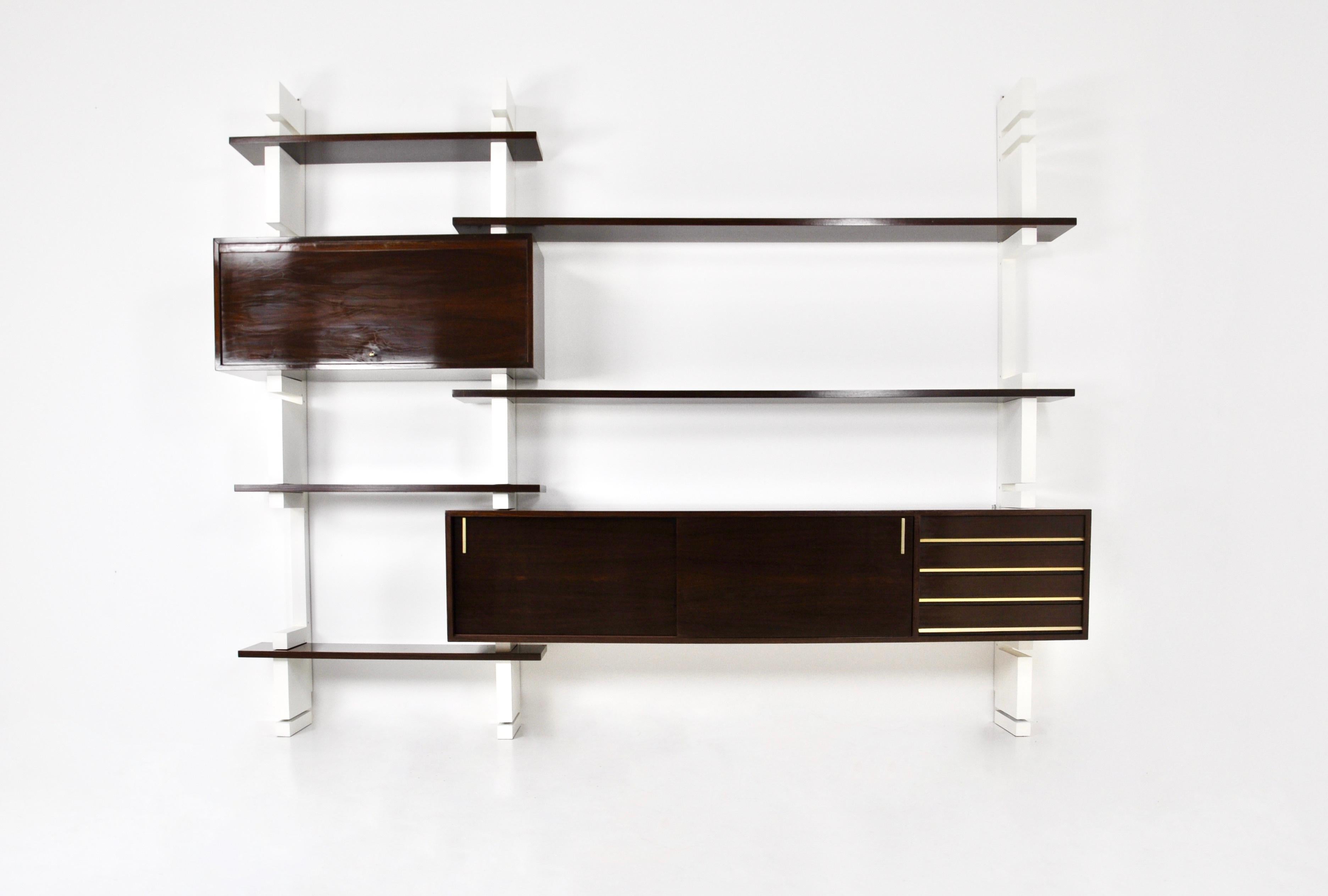 Fully modular wall unit in wood and brass consisting of 3 white uprights, 5 boards, a large pedestal with 4 drawers and two sliding doors and a small pedestal with a door containing 2 drawers. Wear and tear due to time and age.
For shipping, request
