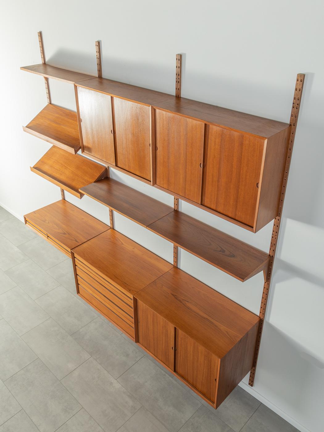 Classic shelving system from the 1960s. The high-quality containers and shelves are veneered in teak. The system consists of three shelves, three containers with cupboard doors, a container with four drawers, a container with two drawers, six