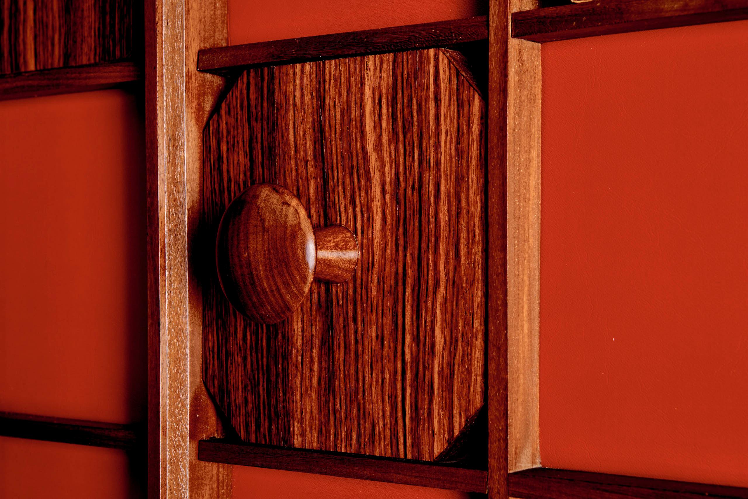 Armoire ou meuble mural de style moderne du milieu du siècle, fabriqué dans les années 1960. Cette pièce frappante présente un fond rouge audacieux encadré par une structure en grille de bois. Chaque unité de grille est accentuée par des panneaux