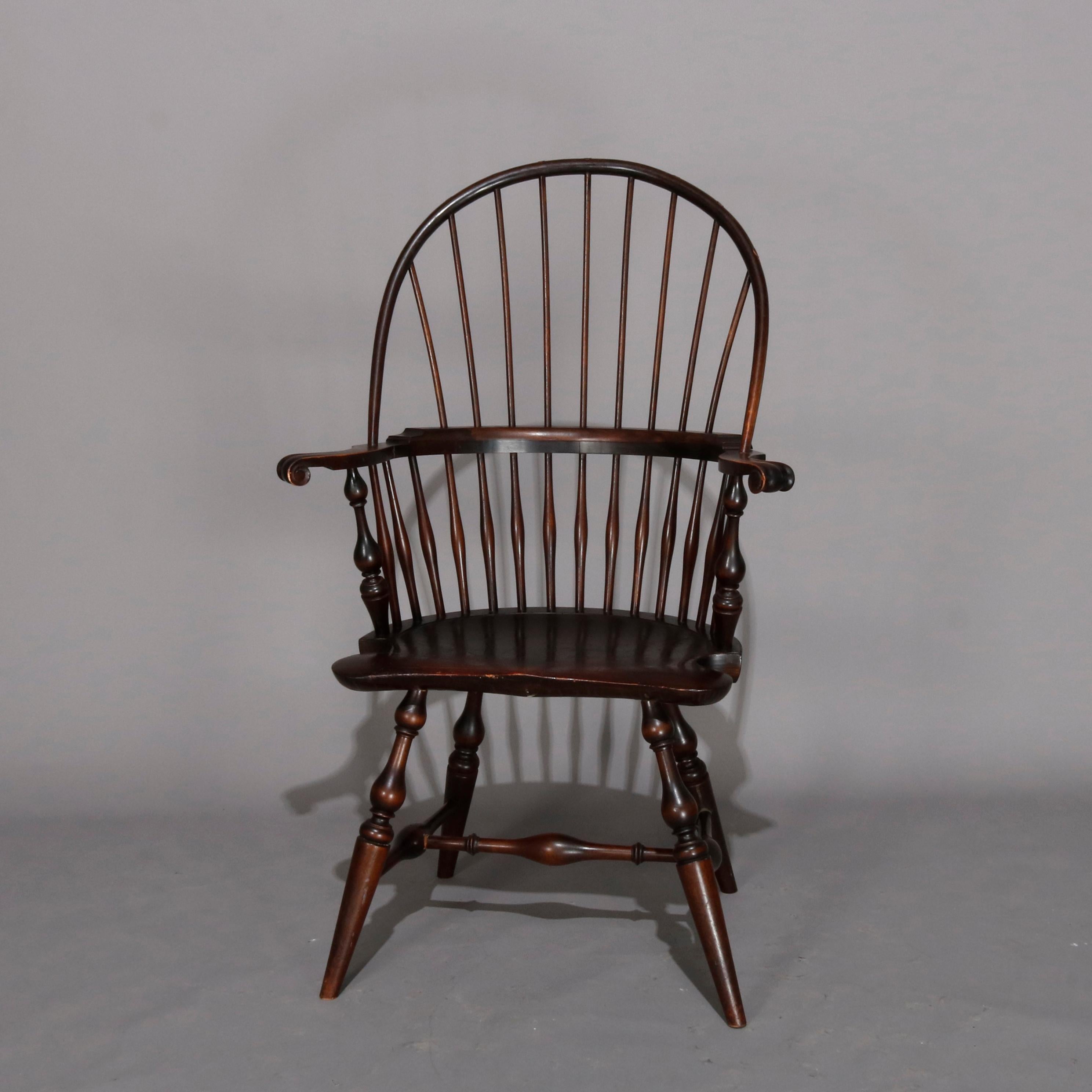 Pair of Windsor armchairs by Wallace Nutting offer oak pegged construction with scroll form and shaped crest surmounting fan-back with turned spindles and scrolled arms, one chair having ebonized finish and the other with a deep brown finish,