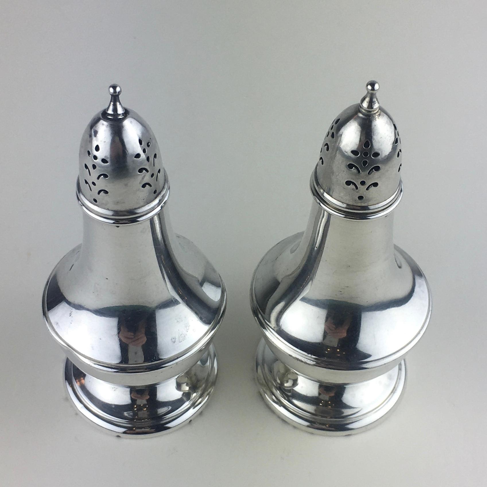 A pair of sterling silver salt and pepper shakers. They are marked “Wallace Sterling 243” to the underside.
