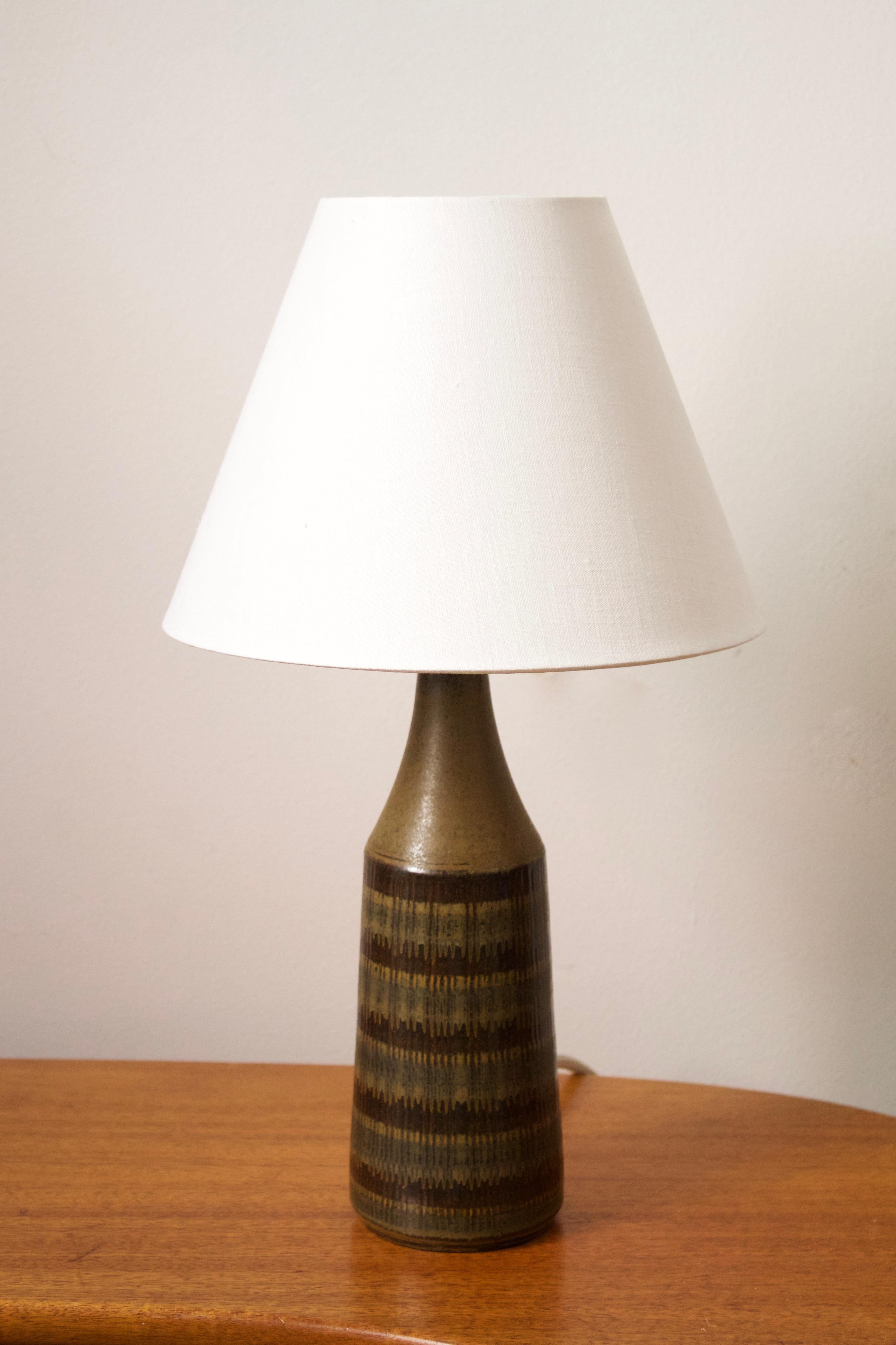 A table lamp. Designed and produced by Wallåkra, Sweden, 1960s. Features simple hand-painted and incised decoration.

Stated dimensions exclude lampshade. Height includes socket. Sold without lampshade.

Glaze features a brown-green color.

Other