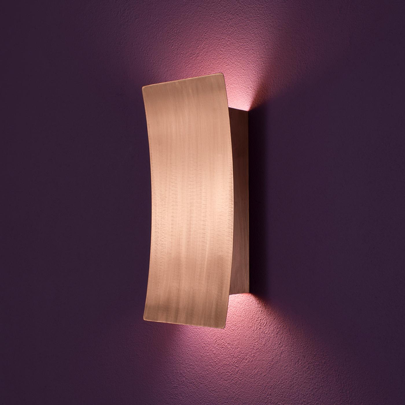 Emitting an evocative, soft light, this sconce is available in bright brass or satin steel. It features an arch-shaped lampshade fixed on a wall diffuser that will boast a warm light at every height. The satin metal captures and spreads the light in