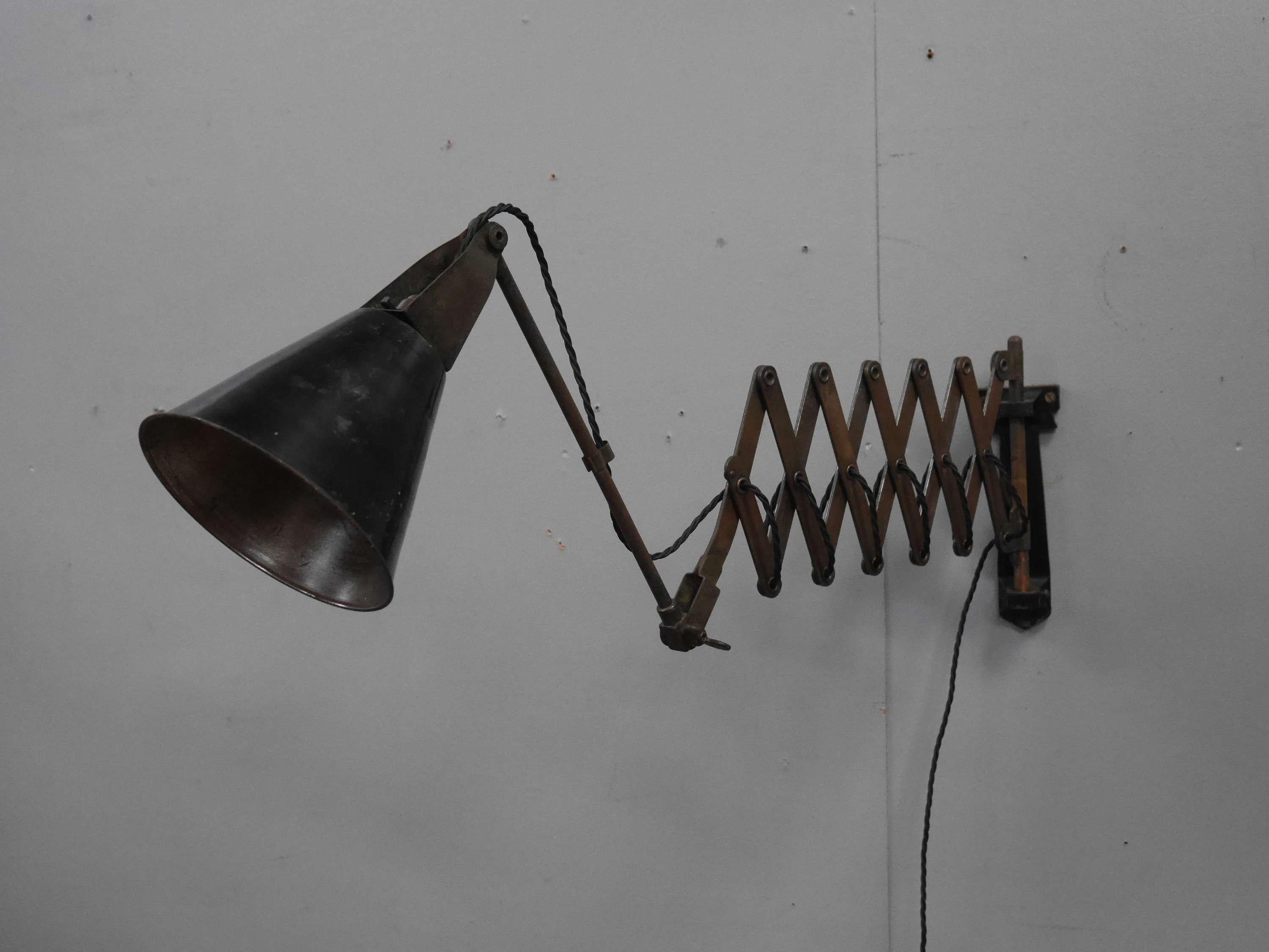 A vintage industrial Walligraph scissor lamp.
A fantastic Walligraph 'Radialite' lamp with a heavy cast iron wall mount supporting an articulated riveted scissor movement in the original 'coppered' finish & conical spun steel shade. 
A handsome &