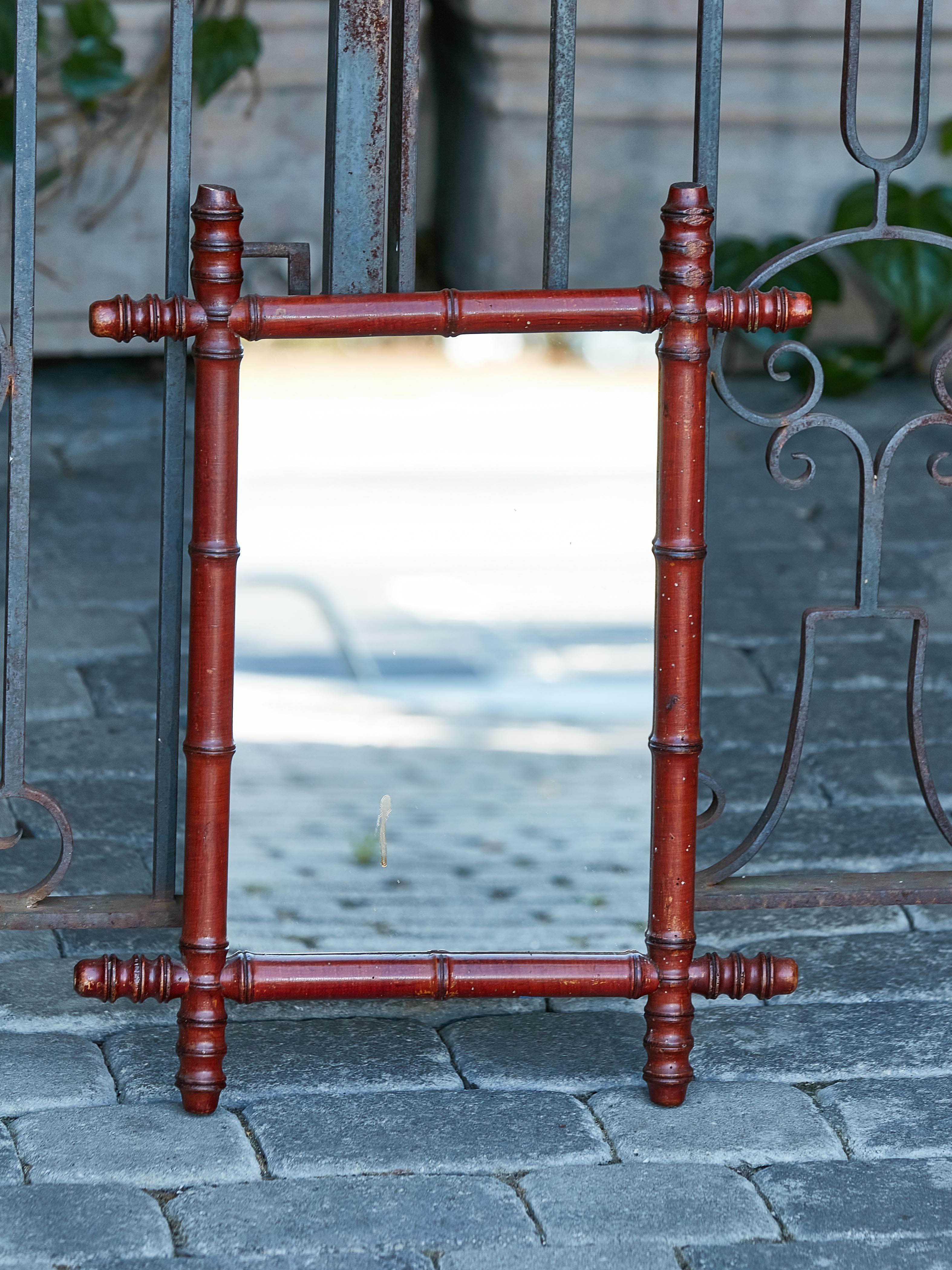 A French 1920s walnut faux-bamboo mirror with rich brown color, reeded accents in the intersecting corners and small proportions. Step into the elegance of the Roaring Twenties with this French walnut faux-bamboo mirror, circa 1920. Boasting small