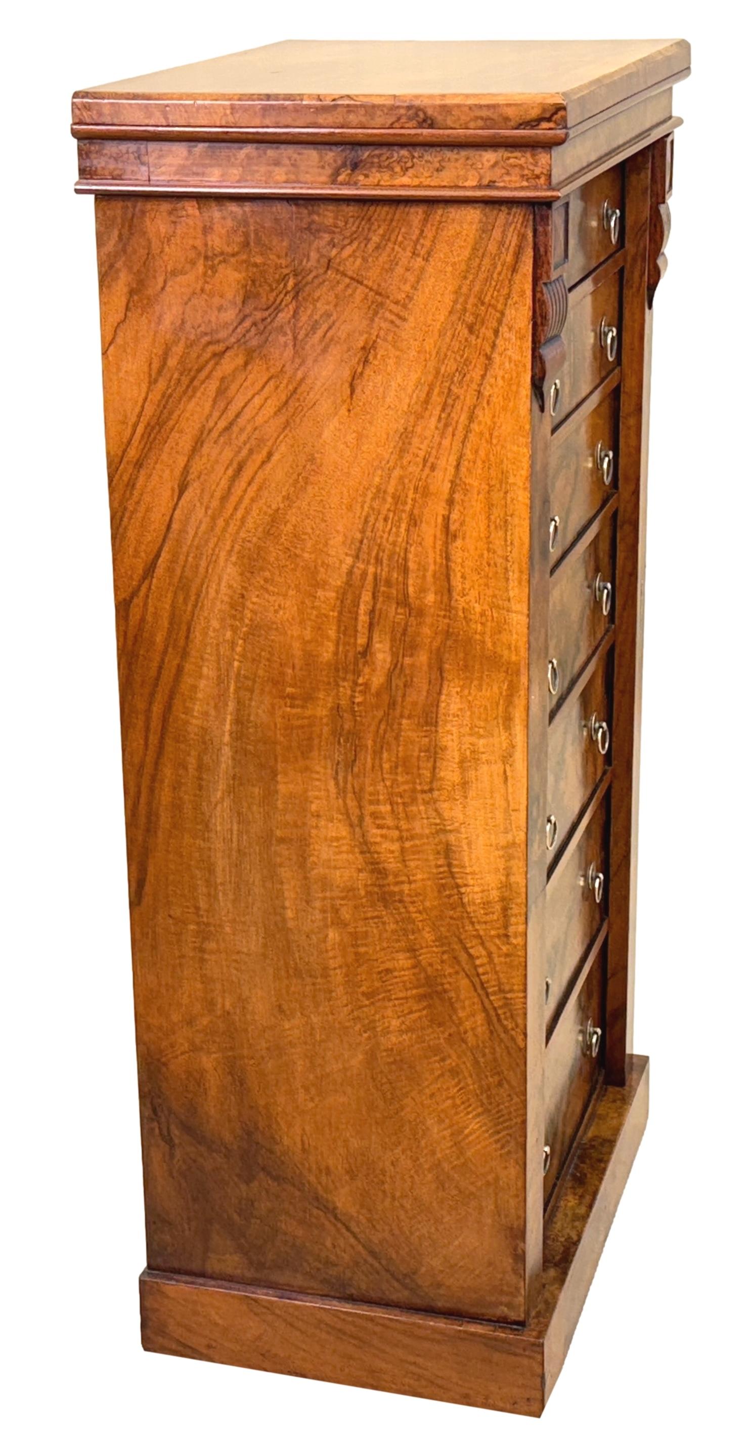 Cassapanca Wellington in noce figurato di fine Ottocento, periodo vittoriano, di piccole e attraenti proporzioni, con piano rettangolare e sette cassetti estremamente ben figurati, con maniglie ad anello in ottone di ricambio, fiancheggiati da