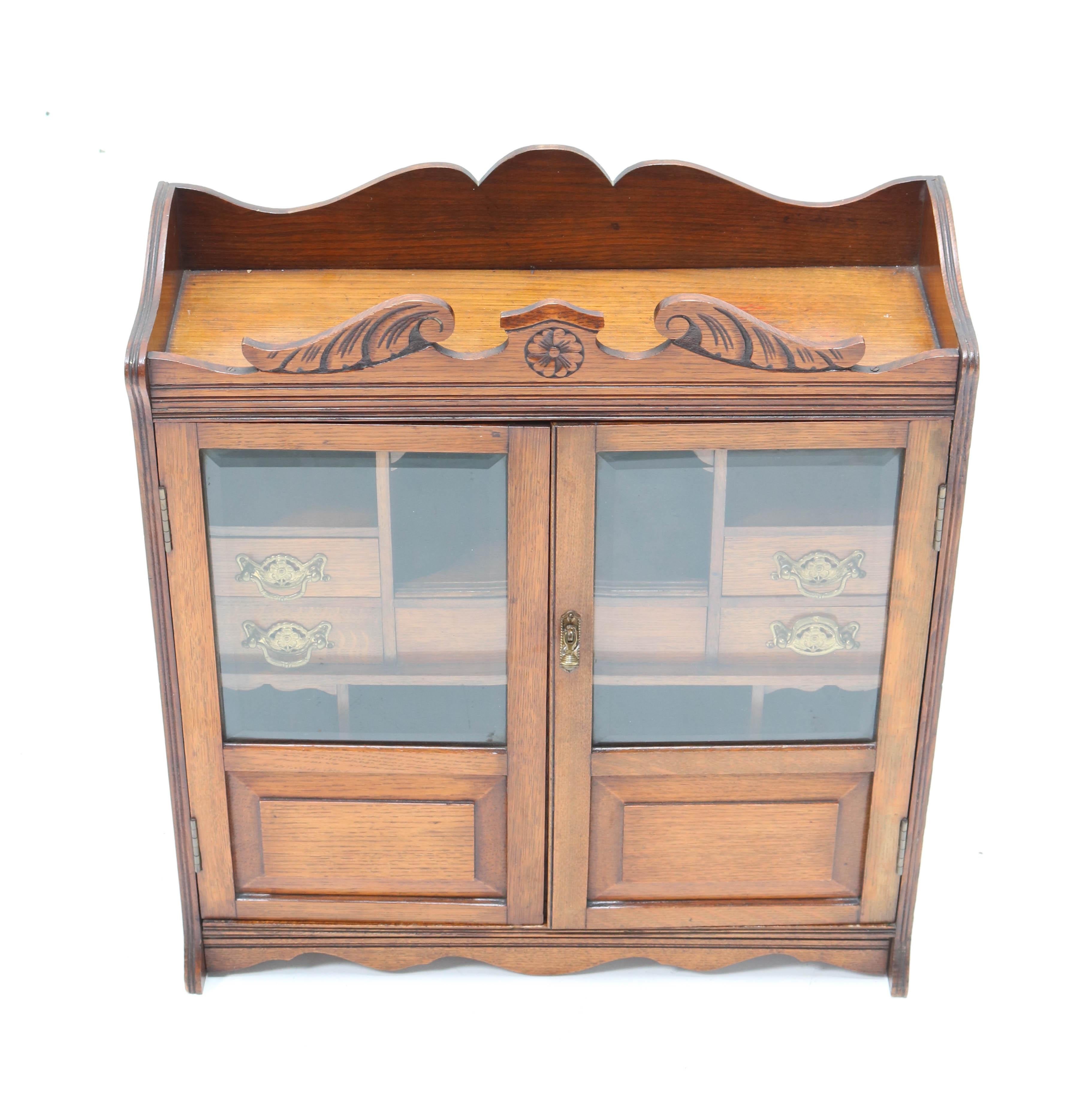 Wonderful and rare Aesthetic Movement wall cabinet.
Striking English design from the late 19th century.
Solid walnut with original beveled glass in the doors.
Original solid brass handles on the seven drawers inside.
In very good original