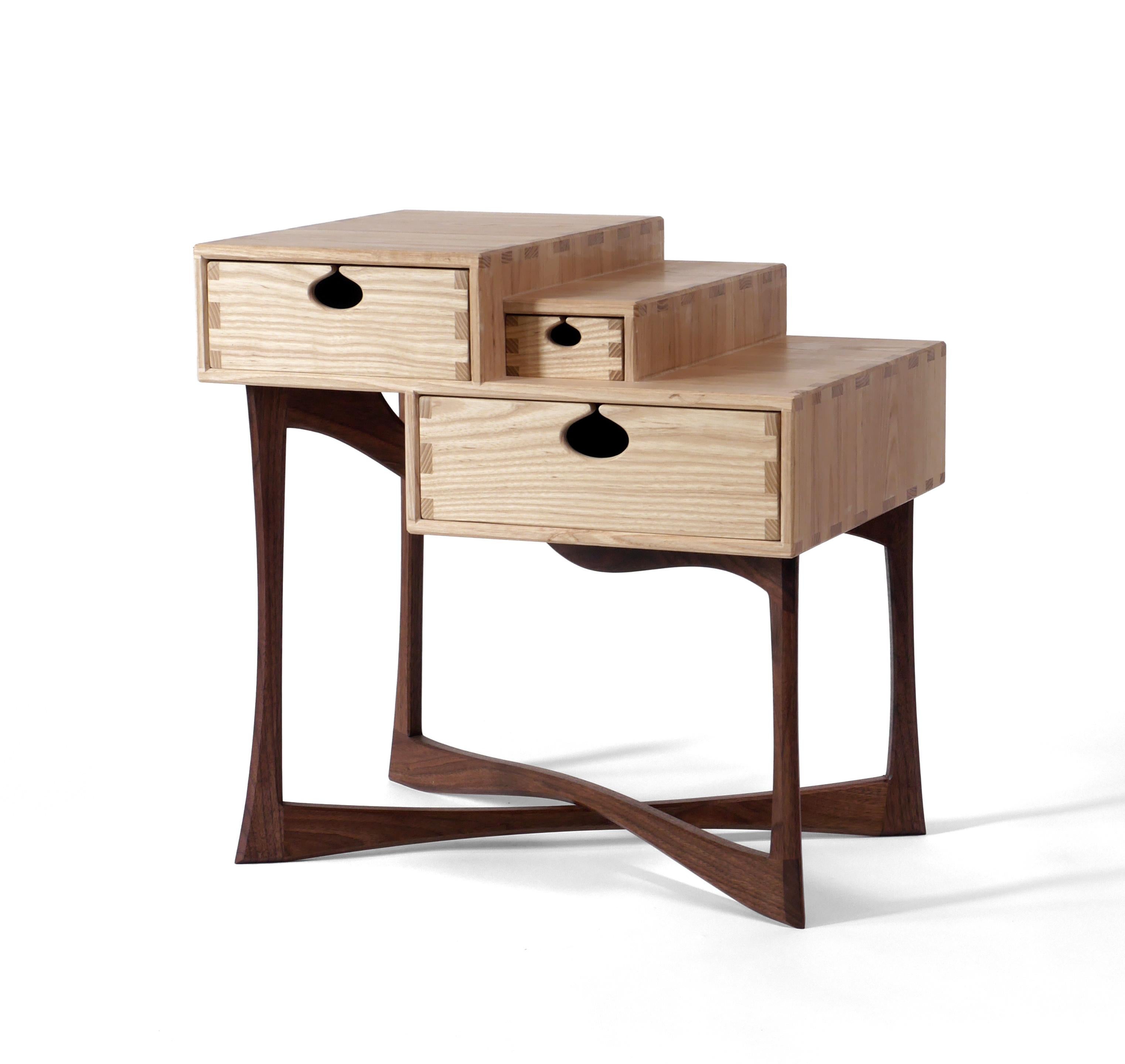 The charismatic Coriolis Side Table is made out of solid black walnut legs that support three drawers mounted on wooden runners in traditional drawer boxes made out of solid white ash. It’s built with exposed joinery that has been carefully designed