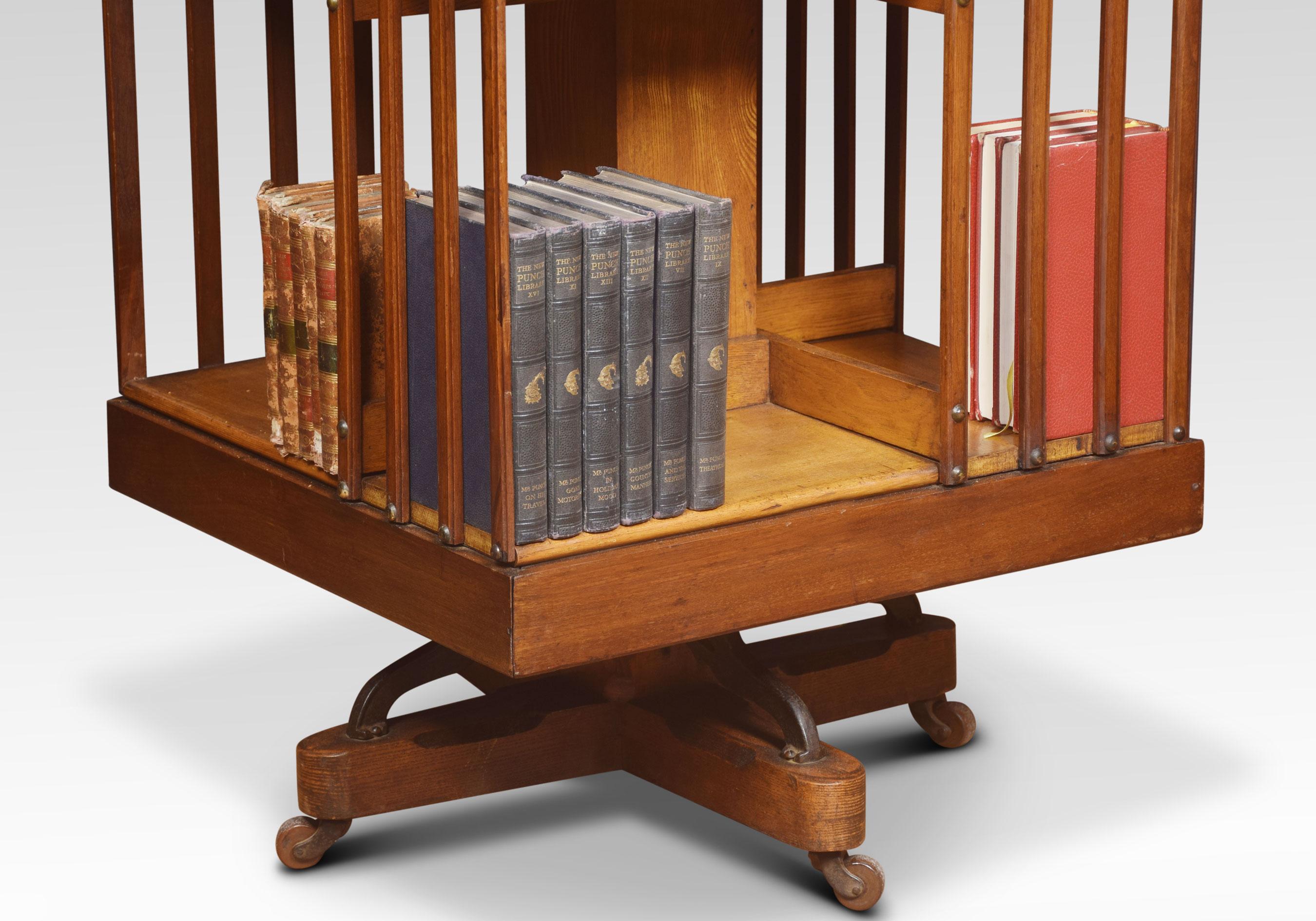 Walnut and ash four tier revolving bookcase, the square moulded top above an arrangement off shelves raised up on cruciform base with metal support. Terminating in brass caps and ceramic castors. The bookcase displaying stamp, the American patent