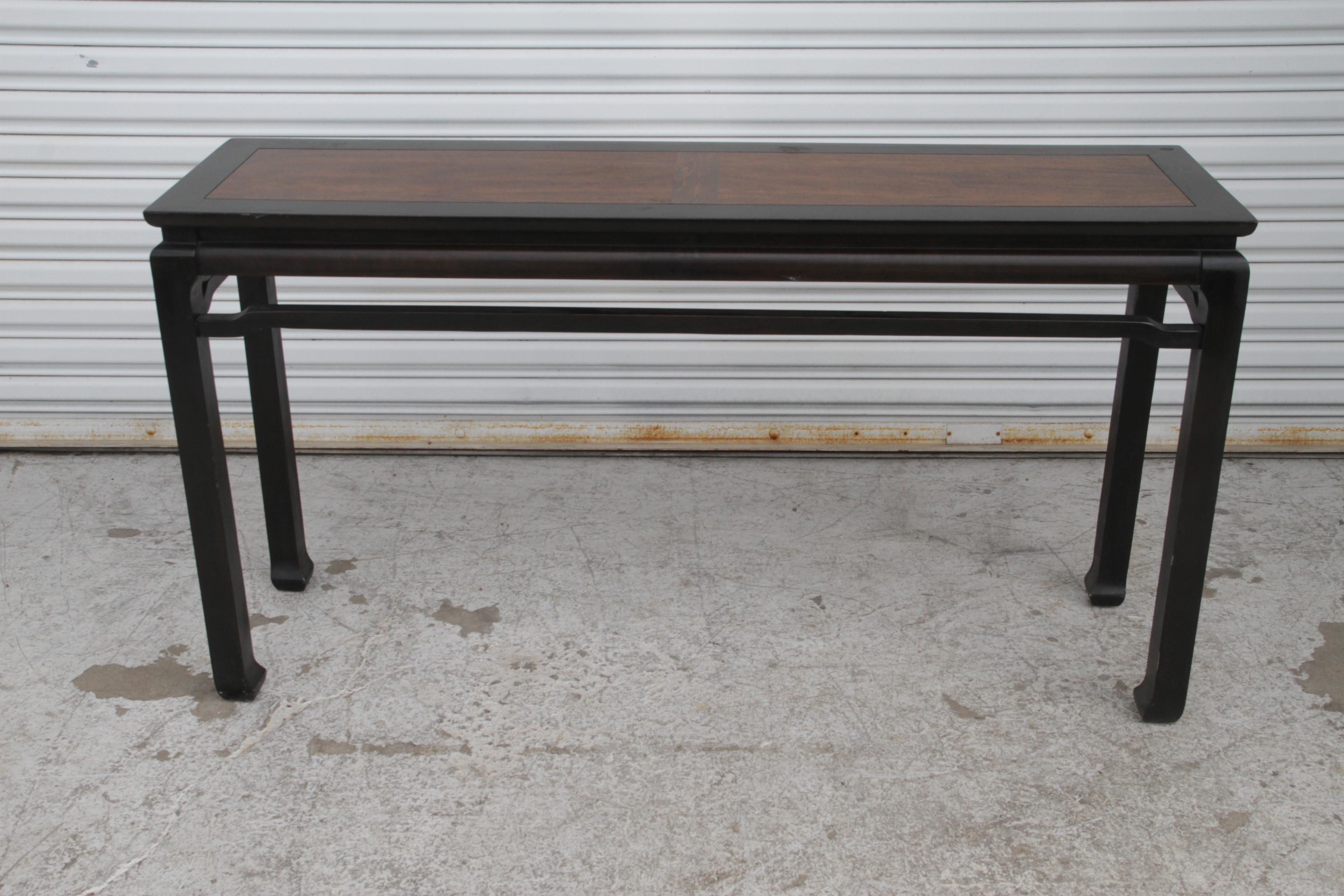A beautiful Ming style console table, supporting a walnut top.

Classic elegant silhouette with a touch of flair at the top and at the feet. Sides have a very dark brown lacquer that appears almost black from afar. The rosewood top has deep rich