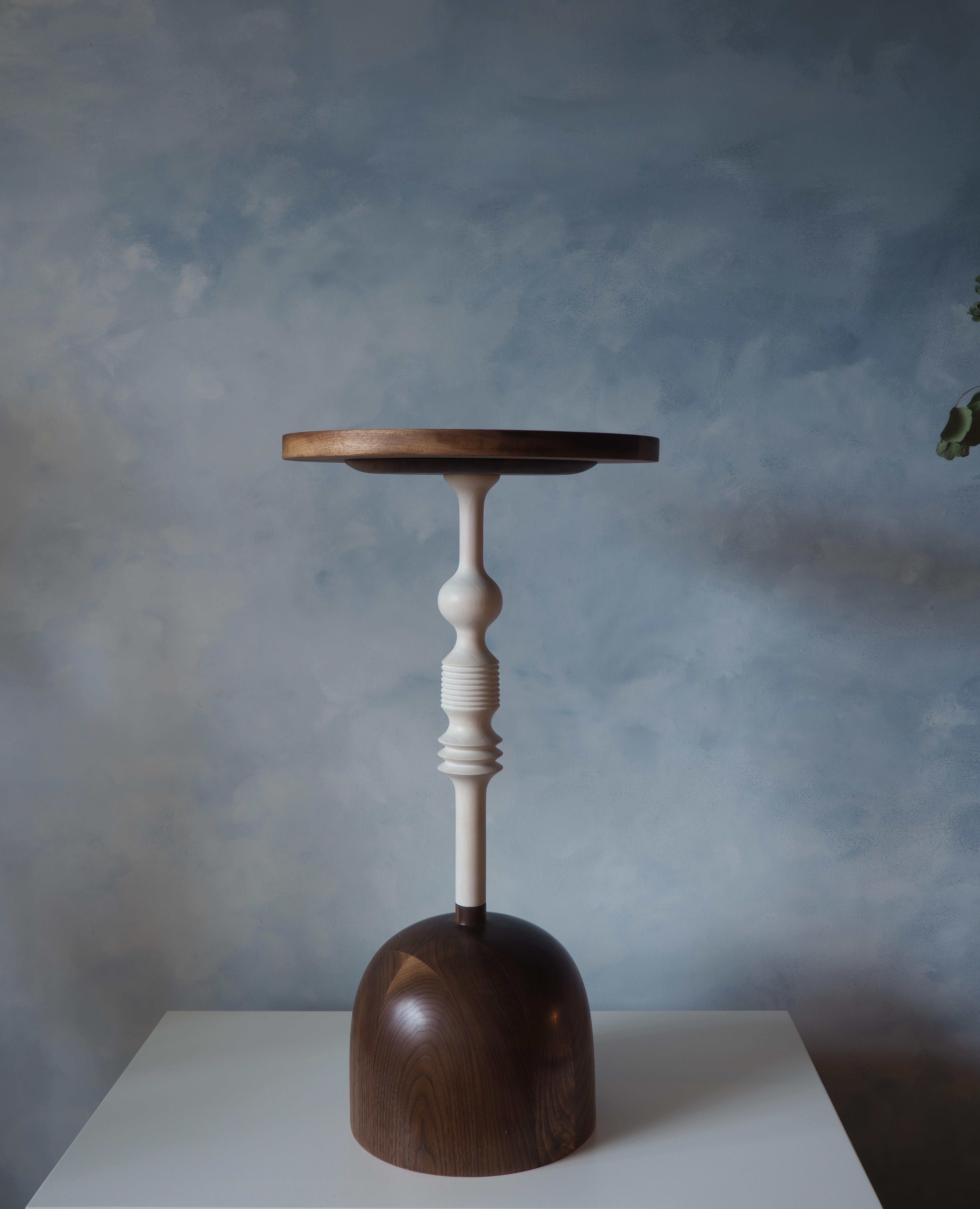 This elegant Walnut side table has been hand turned in our studio. The Maple stem is bleached and given a subtle white finish. The base is turned out of solid walnut and finished with a oil wax blend.

The table top has a ridge to help secure your