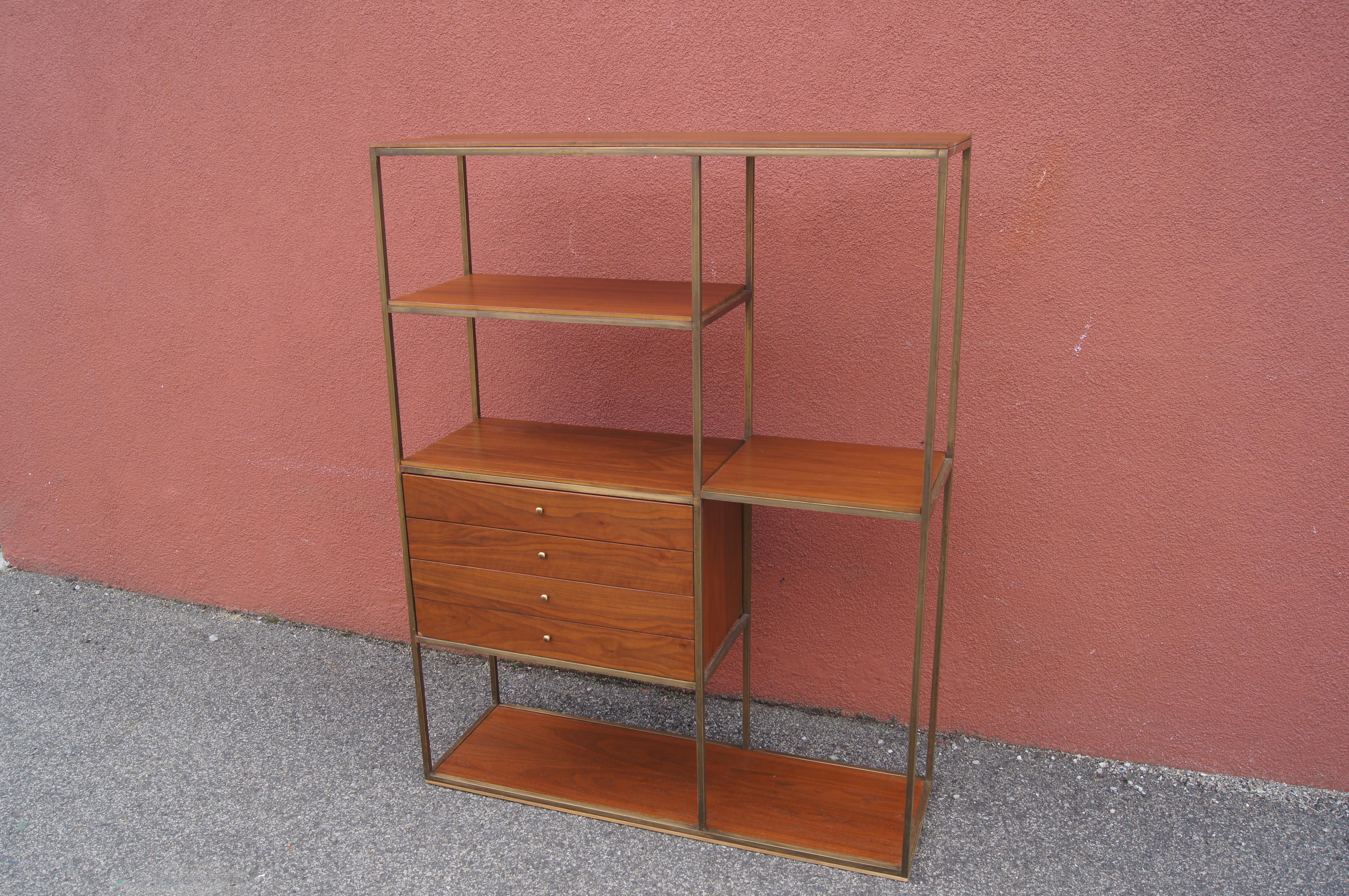 This midcentury étagère by Furnette, in the clean-lined style of Paul McCobb, features brass supports and trim with a walnut base and top. On the left, a shelf floats above a case with four shallow drawers, also in walnut, on the left, a single,