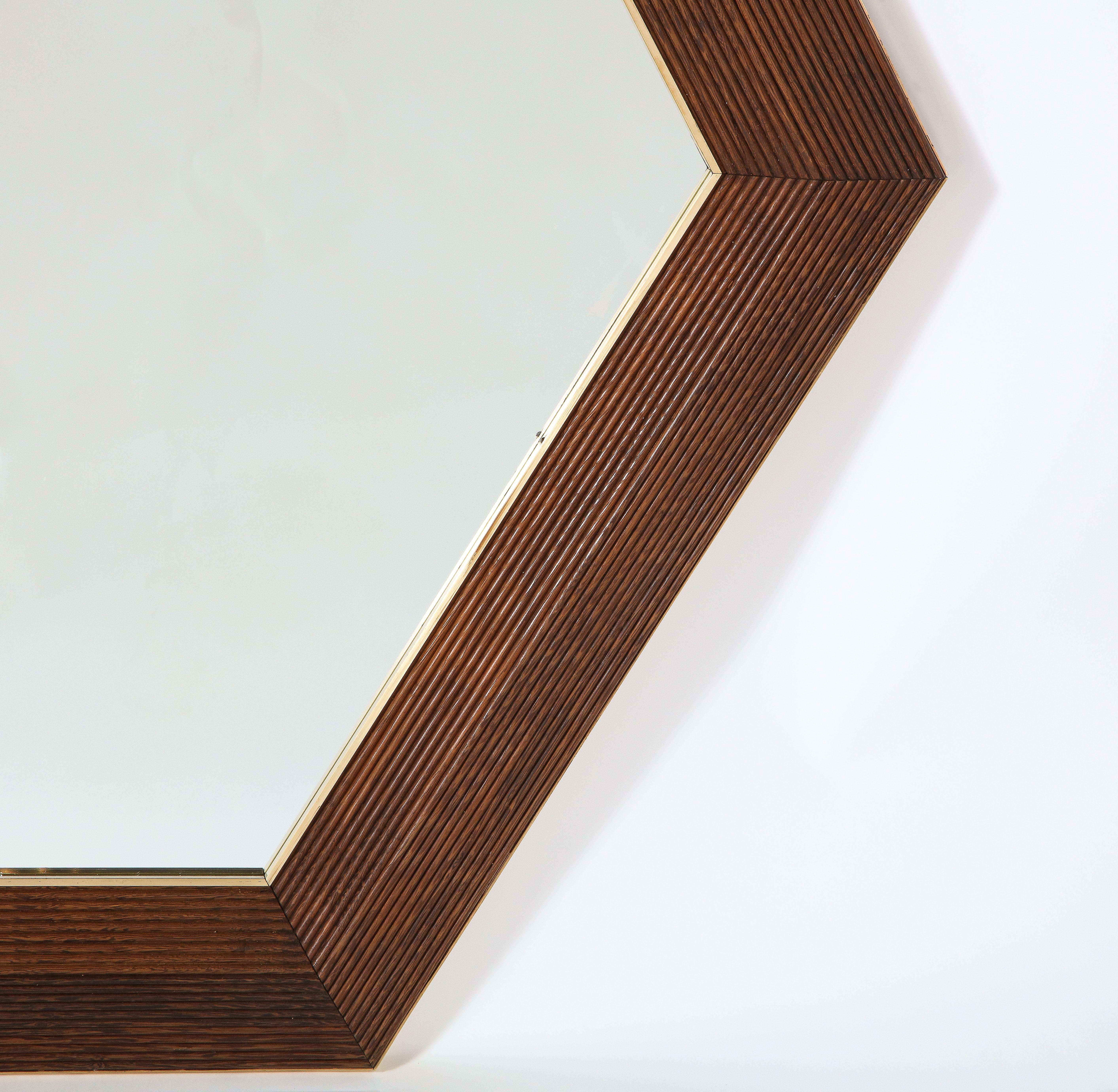 Carved walnut hexagonal shaped mirror with brass surround.  Majestic in scale, with beautiful and rich grained walnut and simple brass trim. 
Italy, contemporary 
Size: 48