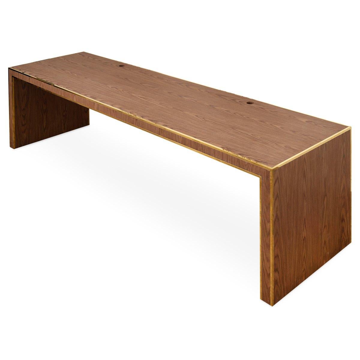 Make a statement in your office with this handsome oversized desk in natural walnut veneer with brass edge detailing. No drawers, but does include 2 media holes on desk top for cords.