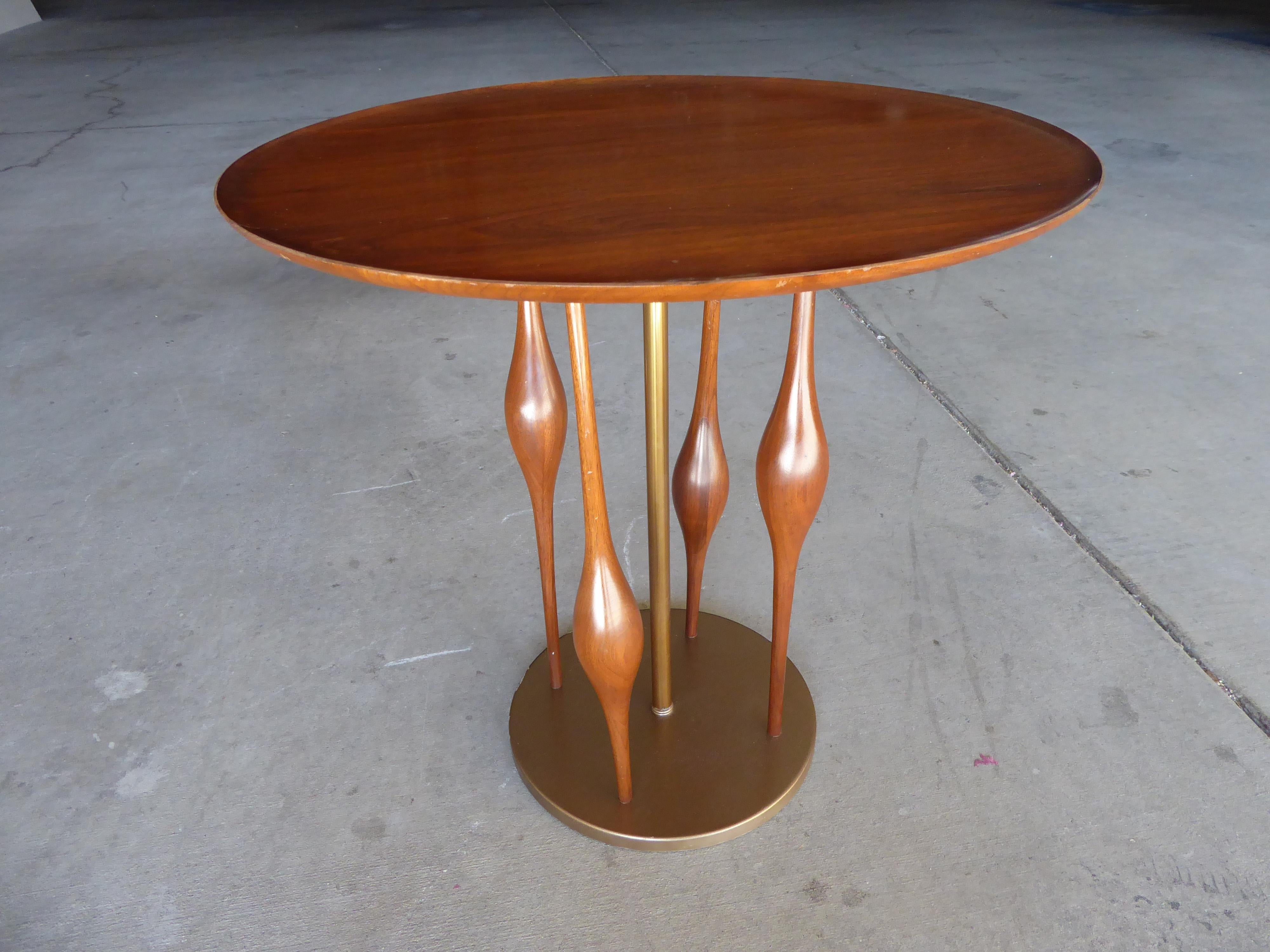 A walnut and brass side table attributed to Modeline of California, circa 1950s. This attribution is based on the visual similarities of the table's base to the details of lamps made by the Modeline Company. The base of the table has a brass