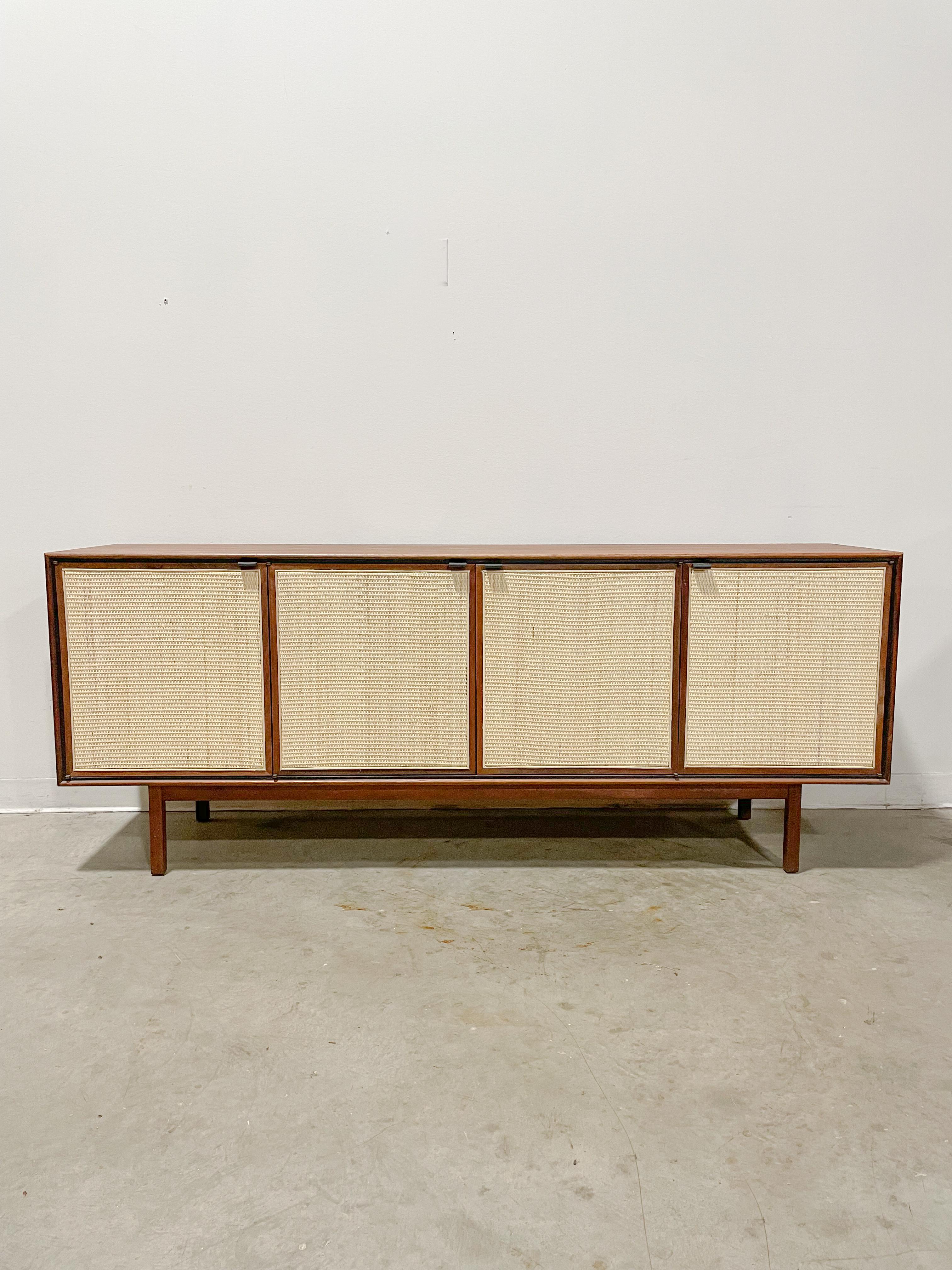 Beautifully proportioned sideboard designed by Jack Cartwright and made by Founders Furniture in the 1960s as part of their Patterns 9 group. Walnut case and legs with newly replaced Danish cane weave door fronts. Ample storage with adjustable