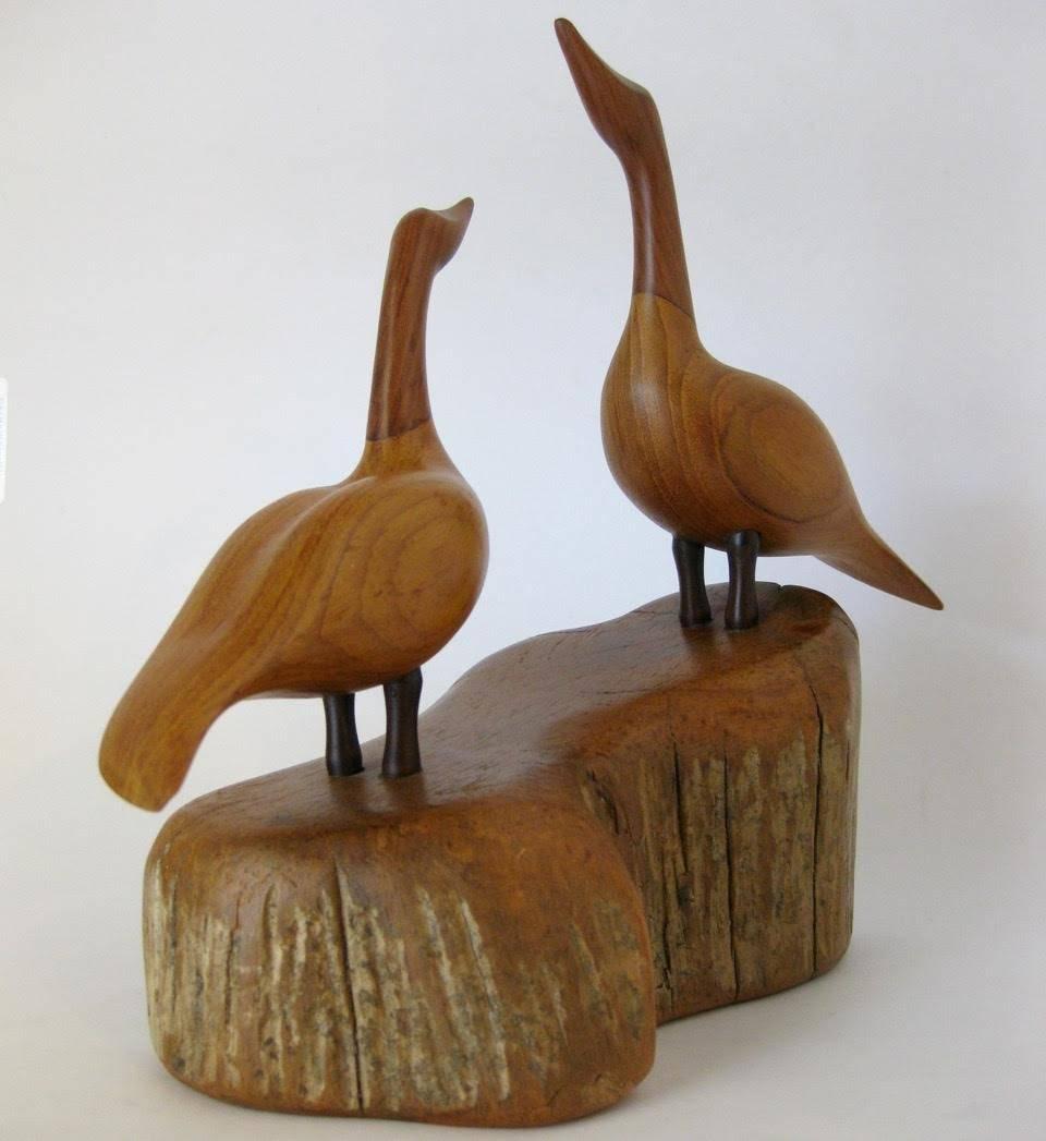 A vintage, hand-carved pair of Canadian Geese, by artist I. Grantins of Lake St. Peter, Ontario, Canada, circa 1980. The geese are made of walnut and cherry with dark wood legs, mounted on a piece of local driftwood from Lake St. Peter. Burned