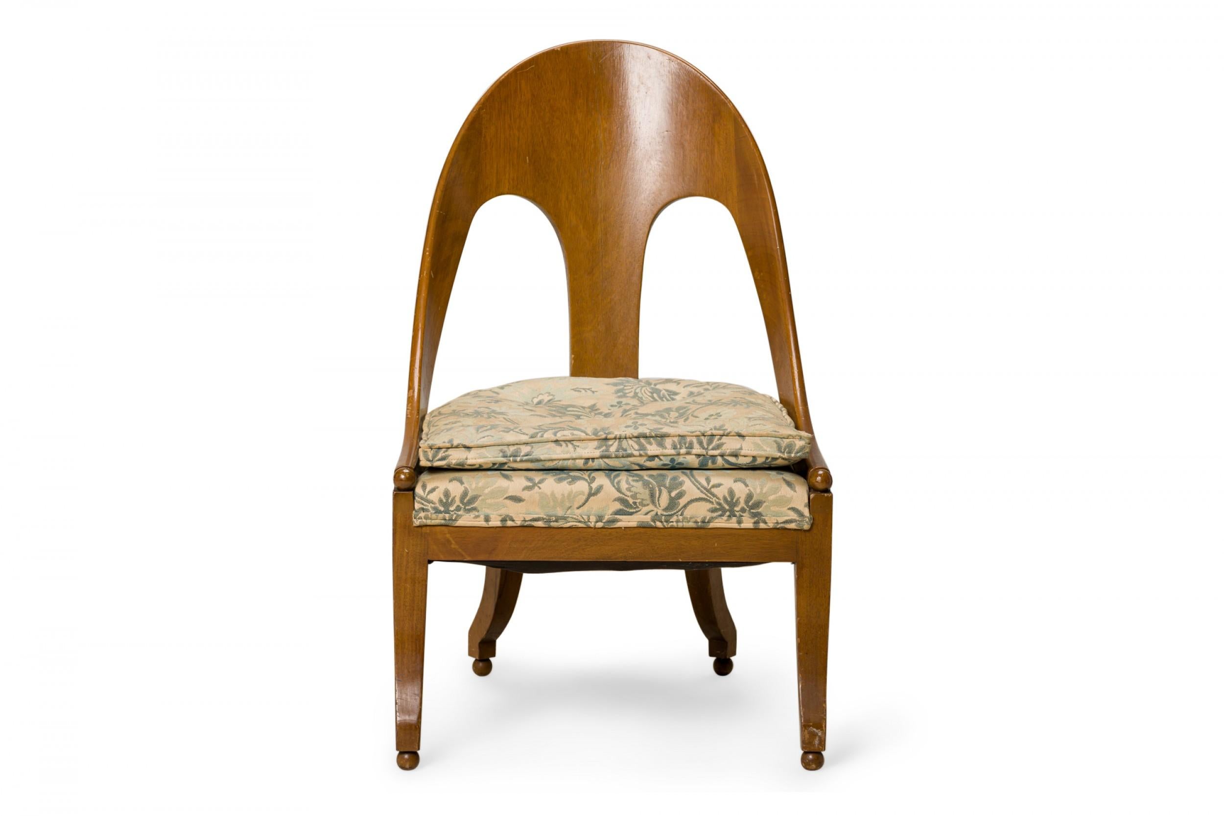 American Mid-Century spoon back side / pull up chair with a walnut frame and a floral beige and blue fabric upholstered seat, resting on four square curved legs ending in ball feet. (Similar pieces: DUF0427-DUF0431)
