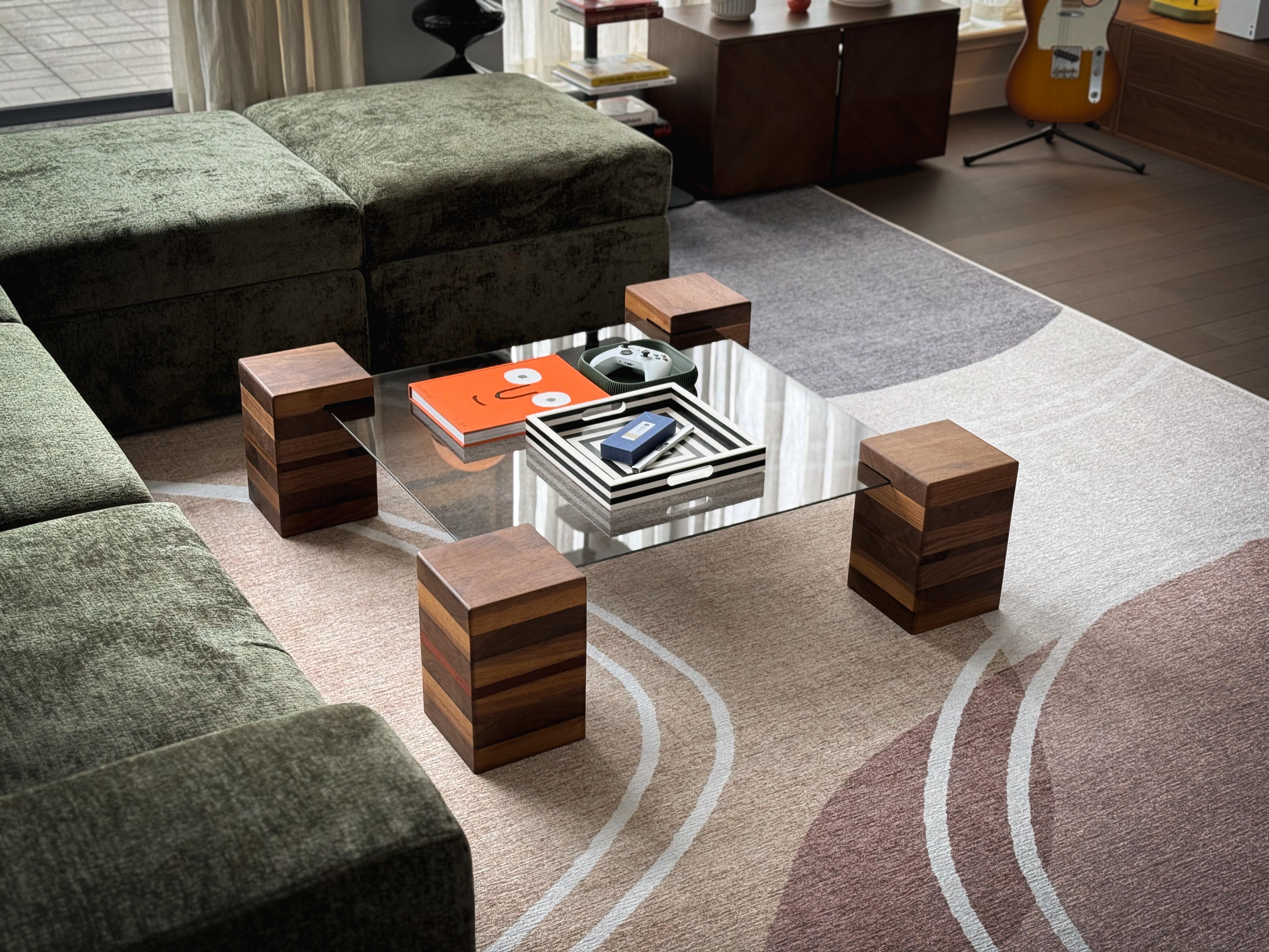 Dieser Couchtisch ist eine Studie über Ausgewogenheit und Schlichtheit und kombiniert dickes, bügelarmes Glas mit der Wärme von massivem Nussbaum. Der Sockel ist aus sorgfältig ausgewähltem Hartholz gefertigt und bietet mit seiner klaren Geometrie
