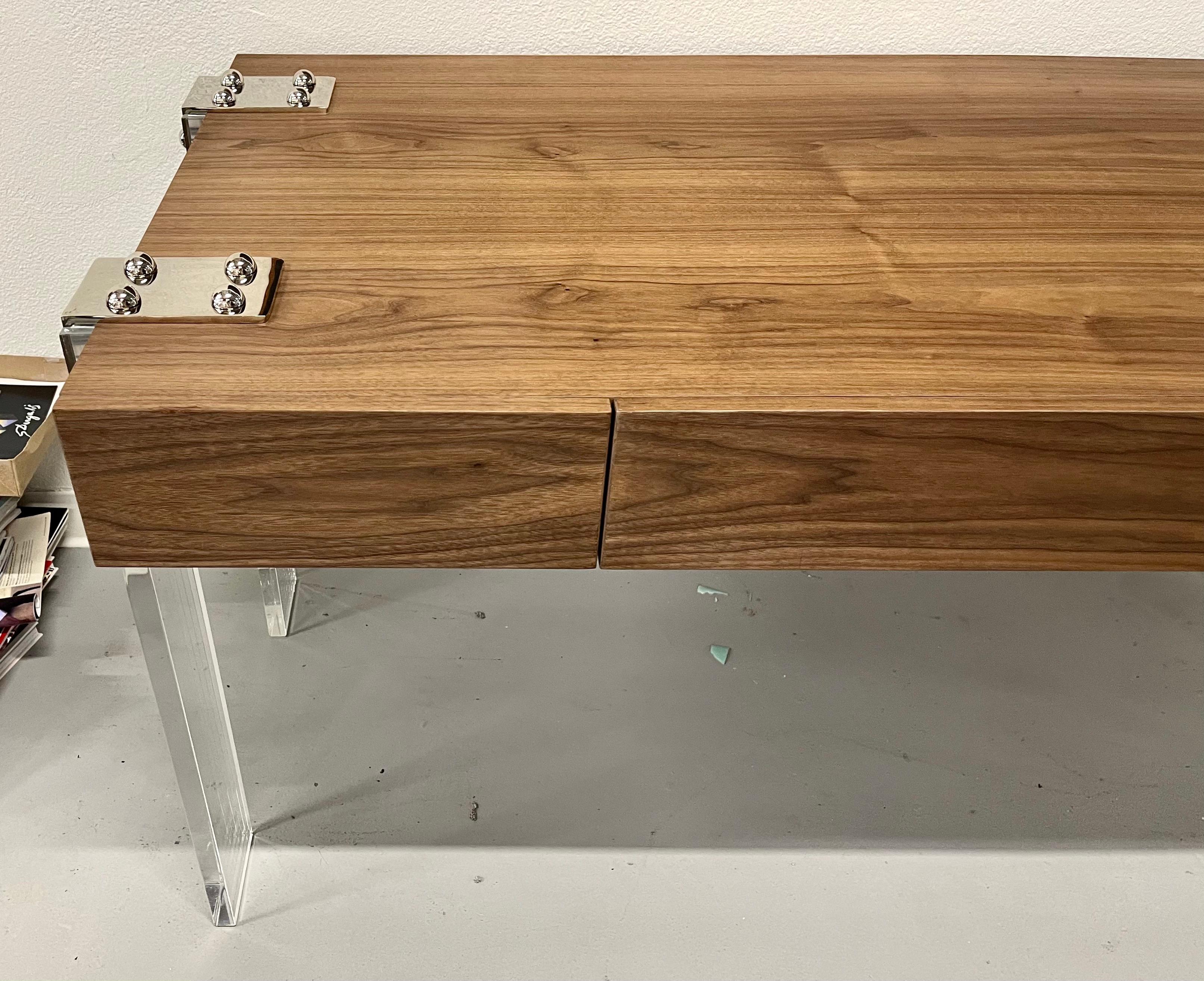 A beautiful custom crafted desk in walnut with Lucite legs and Chrome trim. Elegant and finished on the back with three drawers on the front. 57 inches wide to the outside of the legs, 30 5/8 deep and 29 1/4 tall.